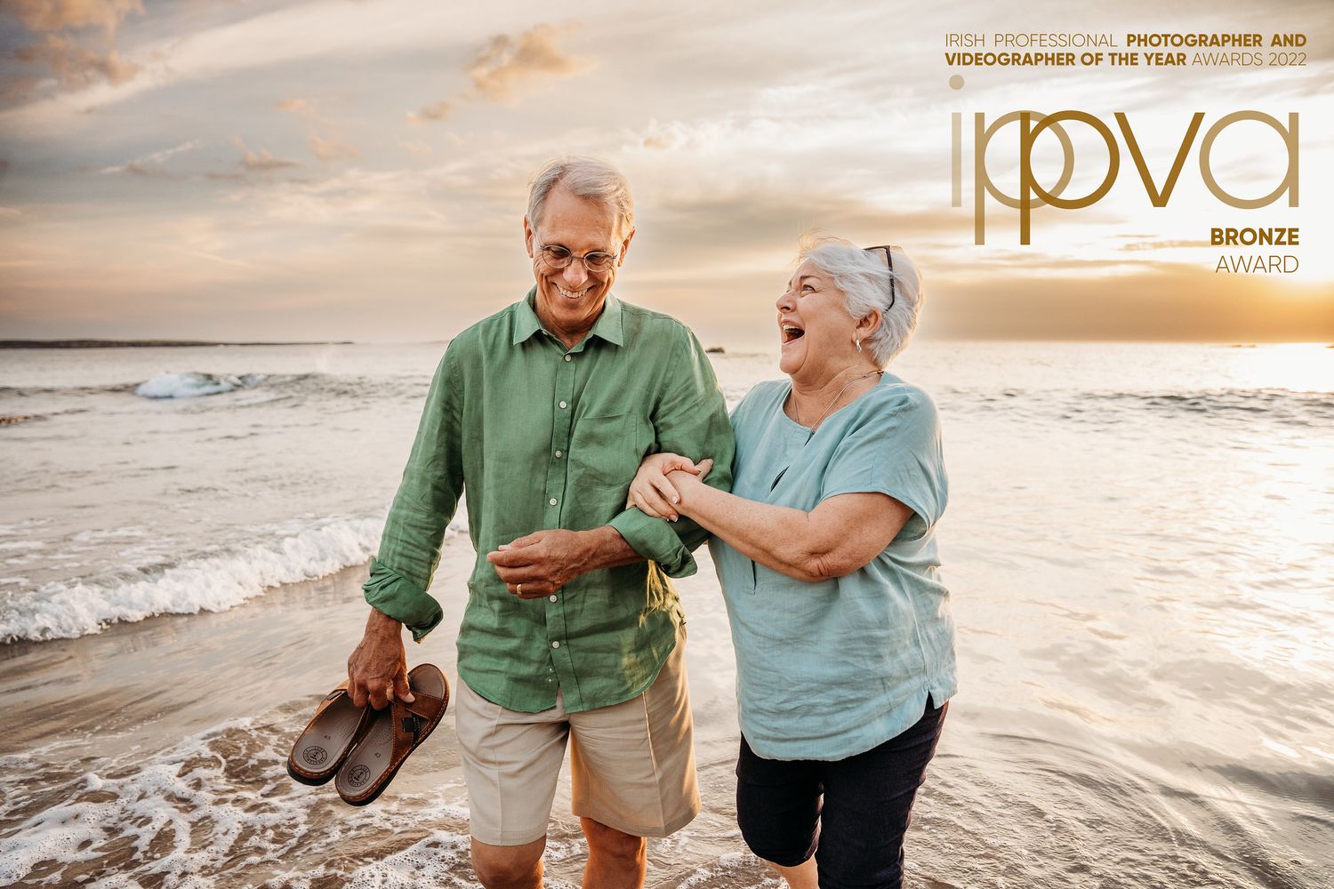 Elderly couple enjoying a romantic sunset stroll along a sandy beach.