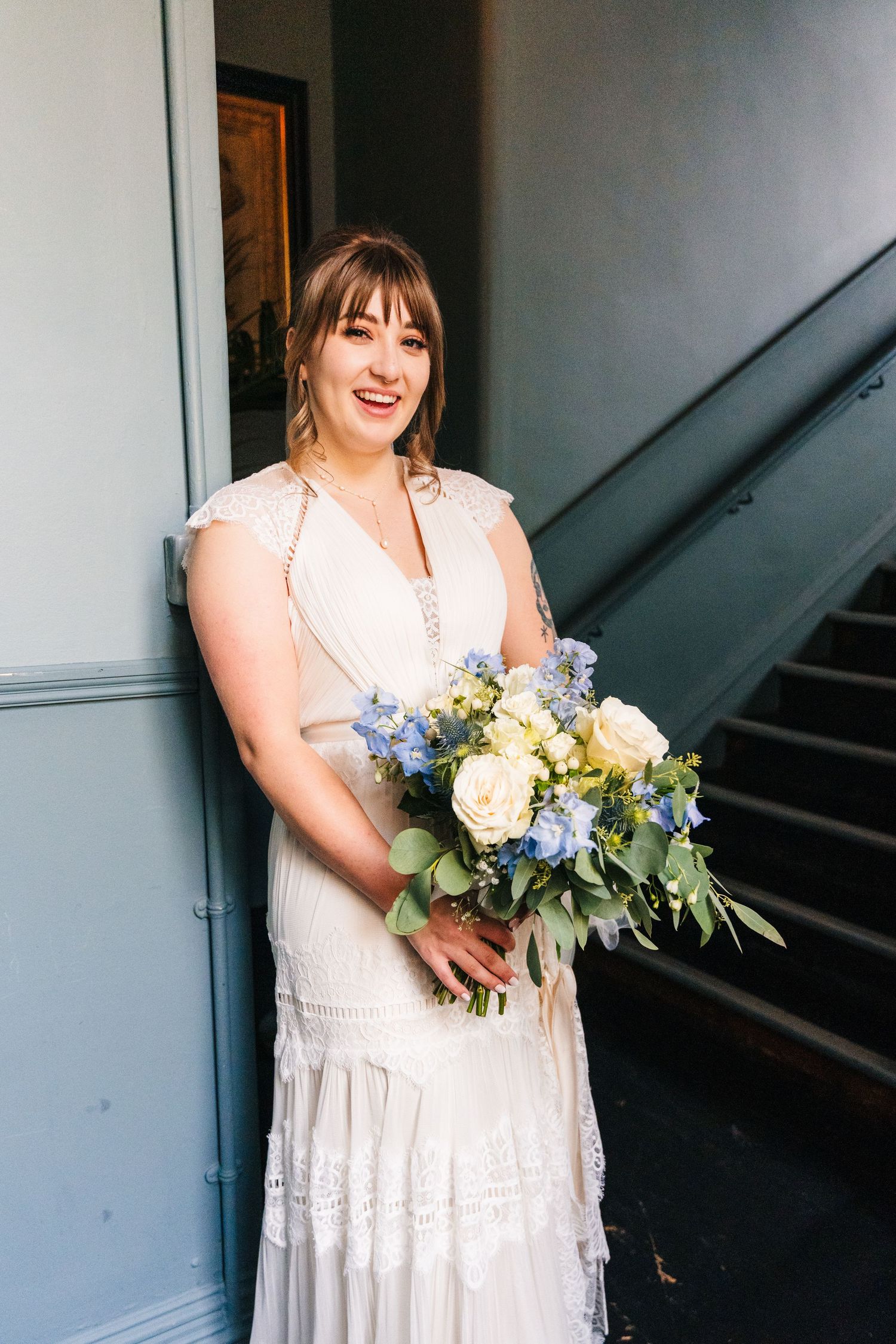 A stunning bridal portrait showcasing an elegant lace dress and beautiful yellow and blue floral bouquet. PHOTOGRAPHER Dublin Ireland Weddin