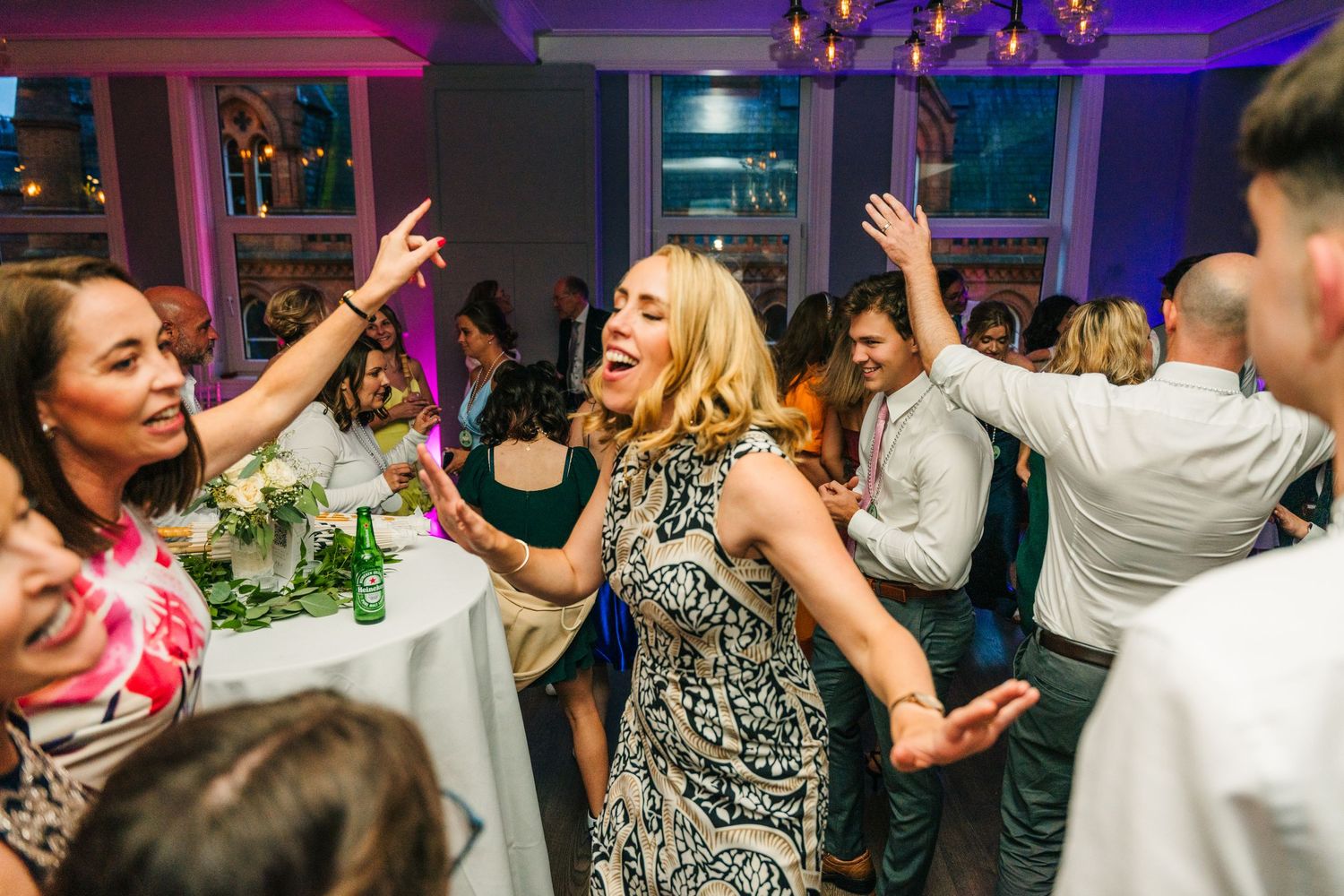 Wedding guests dance enthusiastically under colorful lighting at evening reception. PHOTOGRAPHER Dublin Ireland Wedding