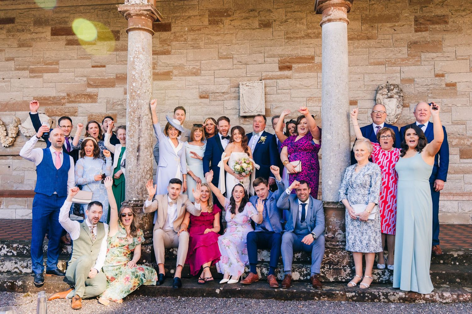 Castle Leslie Wedding Photographer Dublin Wedding party poses together on stone steps with ornate columns for a formal group photo.
