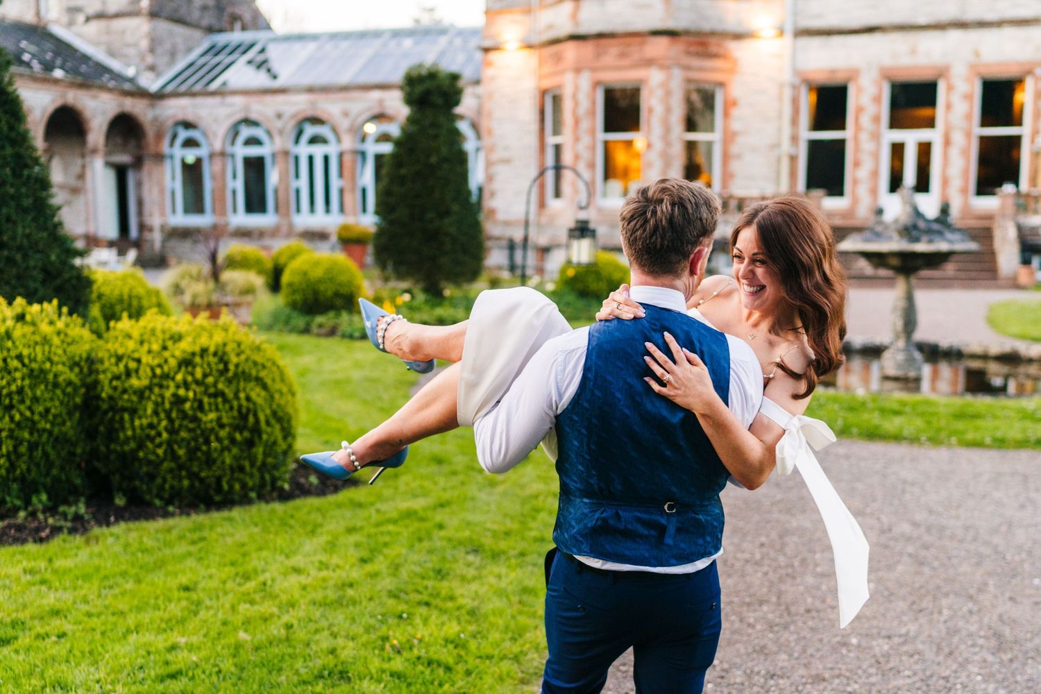 Castle Leslie Wedding Photographer Dublin Joyful wedding moment in front of an elegant stone building with manicured gardens.
