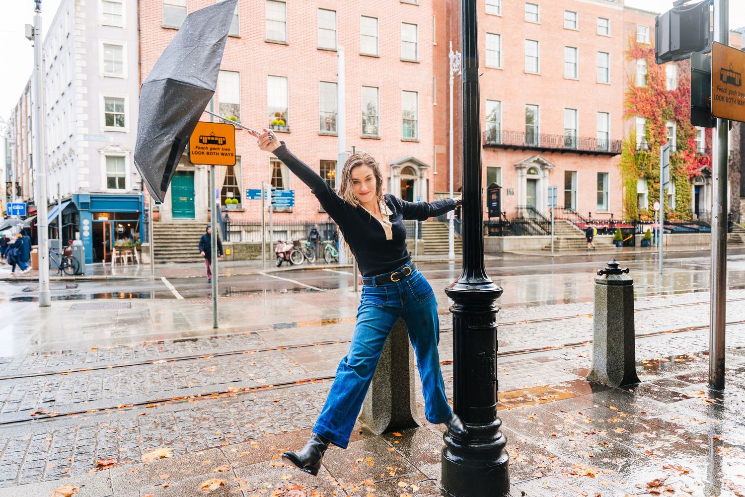People walking on wet city sidewalk with historic buildings in background. professional headshots dublin photographer
