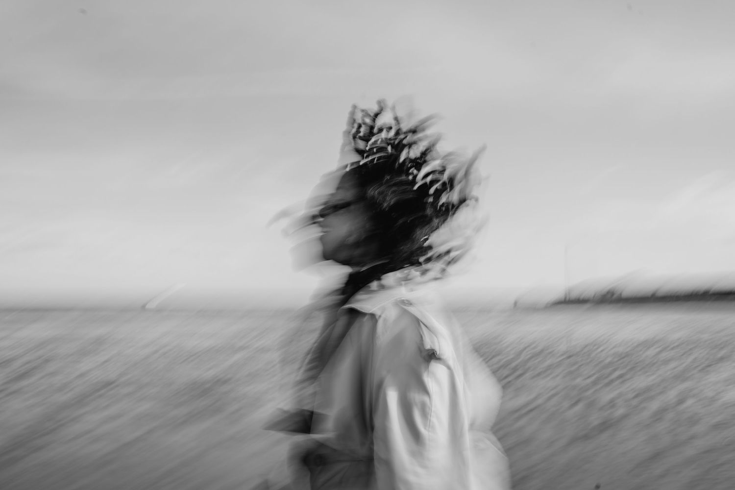 Black and white motion blur portrait of person with windswept hair against blurred landscape background. PHOTOGRAPHER Dublin ireland