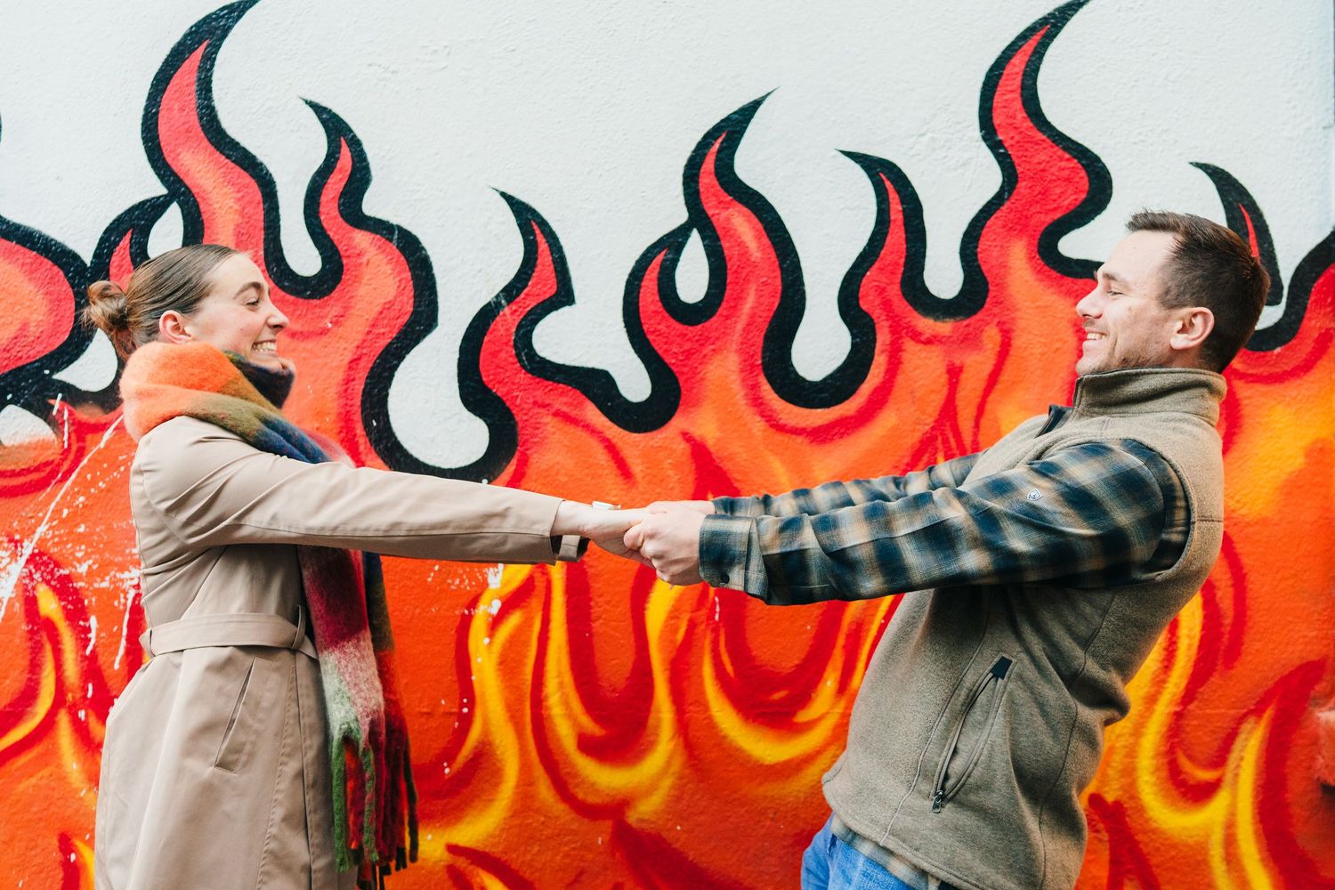 A romantic couple poses against a vibrant wall decorated with red and orange graffiti flames. PHOTOGRAPHER Dublin ireland