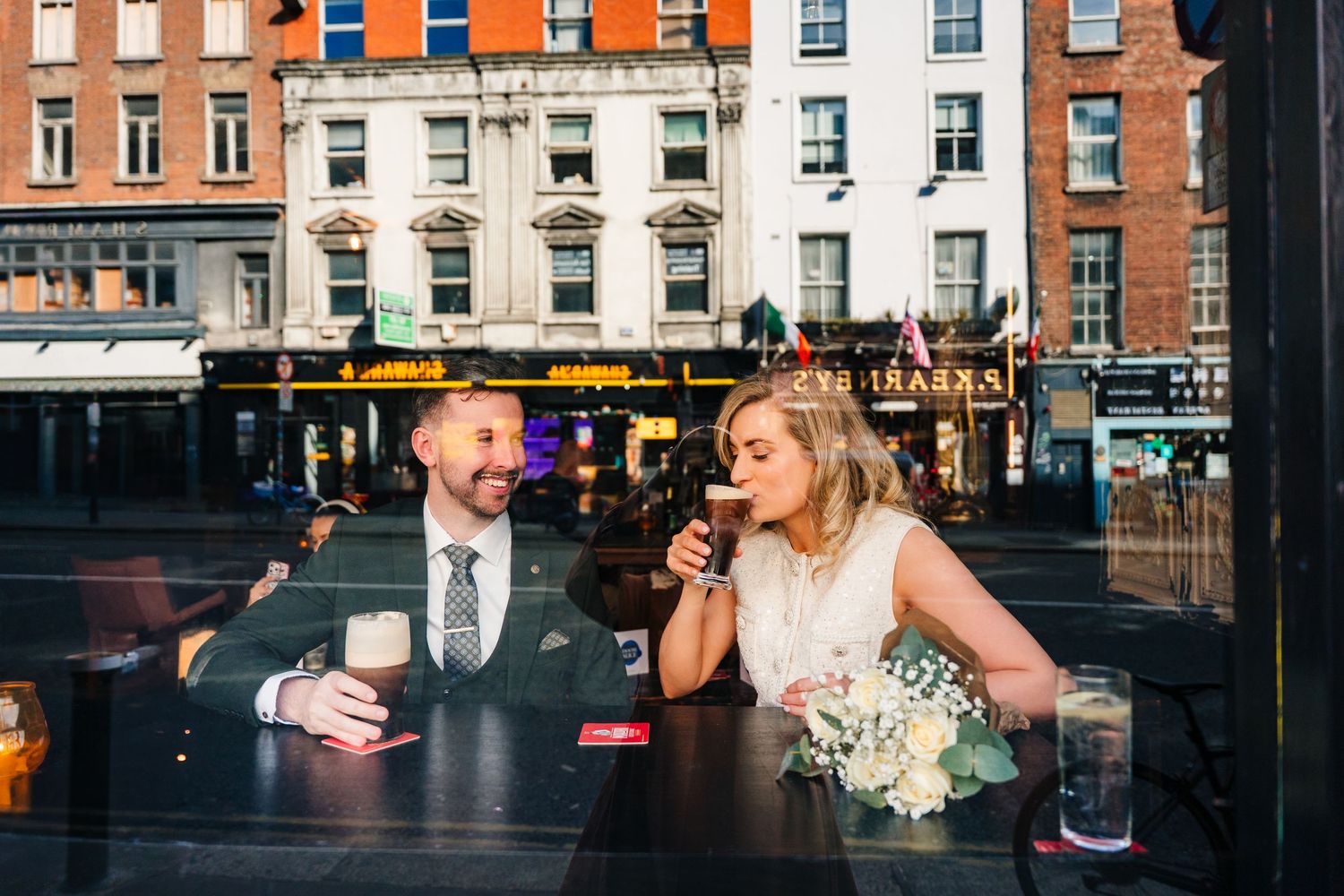 Wedding couple and guests celebrate with drinks and laughter at a historic brick building venue. wedding photographer dublin pricing