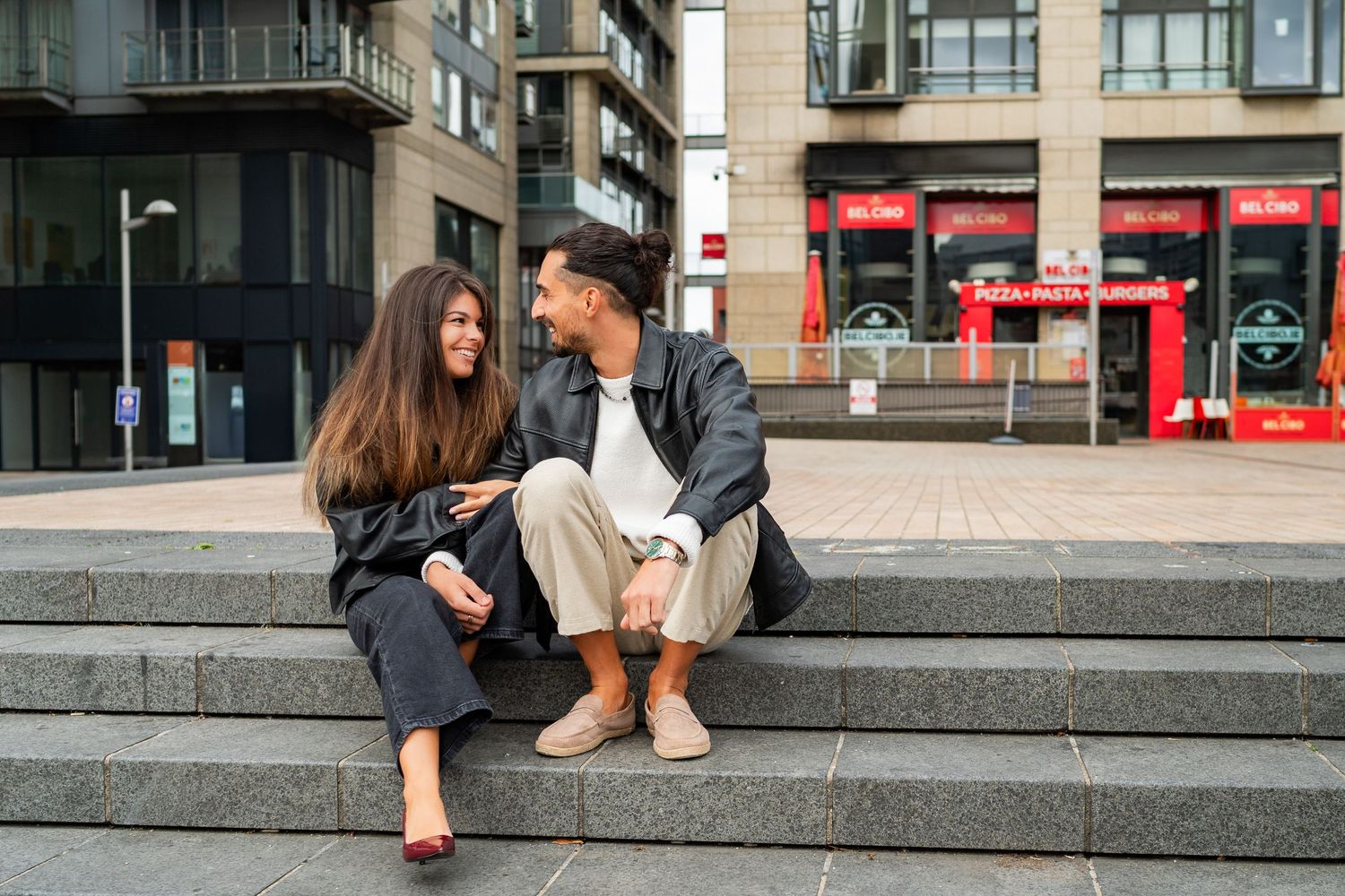 Couple sitting together on concrete steps outside urban building in casual conversation. Couple's Photoshoot PHOTOGRAPHER Dublin