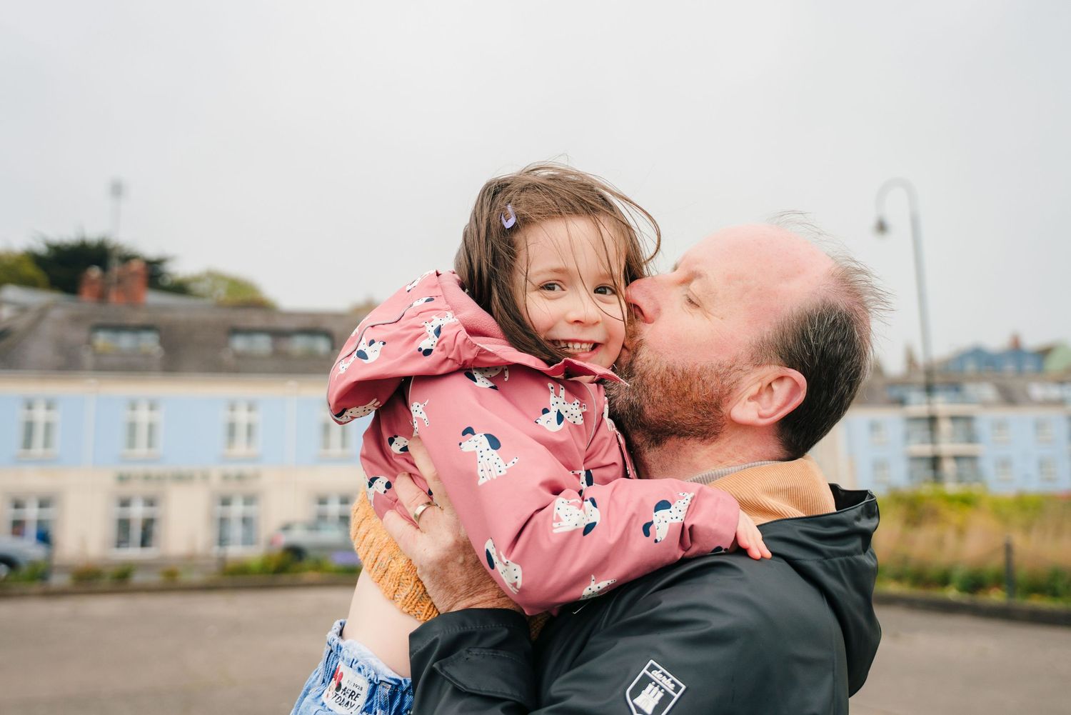 A person in a pink patterned shirt being lifted and embraced in a joyful outdoor celebration moment. PHOTOGRAPHER Dublin