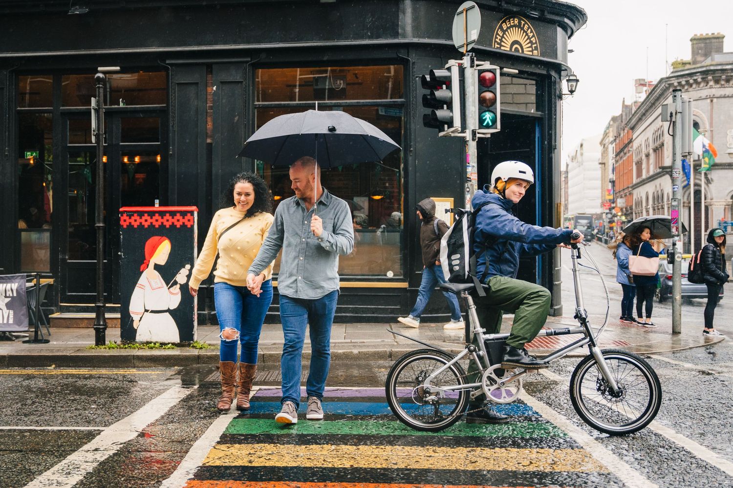 Multiple shots of people walking on rainy urban streets with umbrellas and bicycles visible. Proposal Dublin Photographer