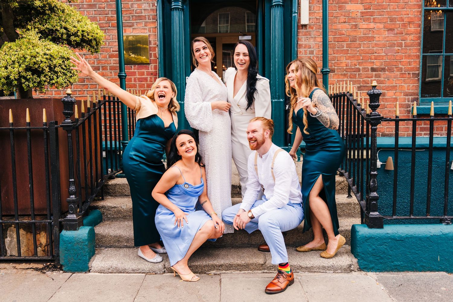 Fun casual group photos taken against a brick building with blue trim and greenery. House Dublin Wedding Photographer