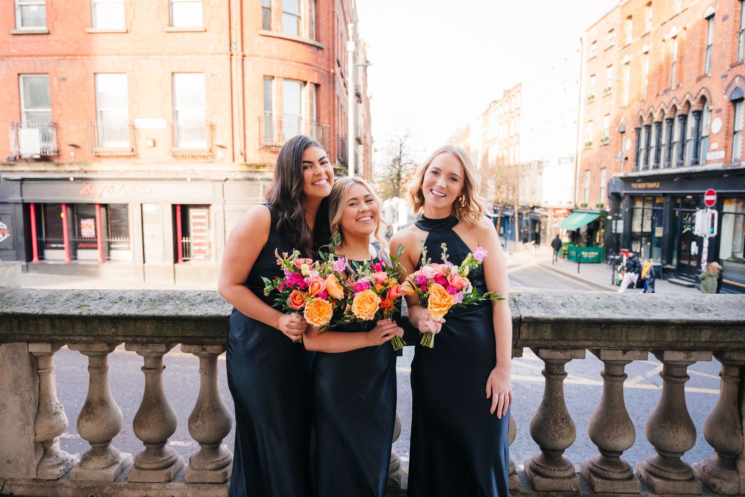Group enjoying a sunny evening on stone steps with historic architecture visible in warm lighting. City Hall Dublin Photographer