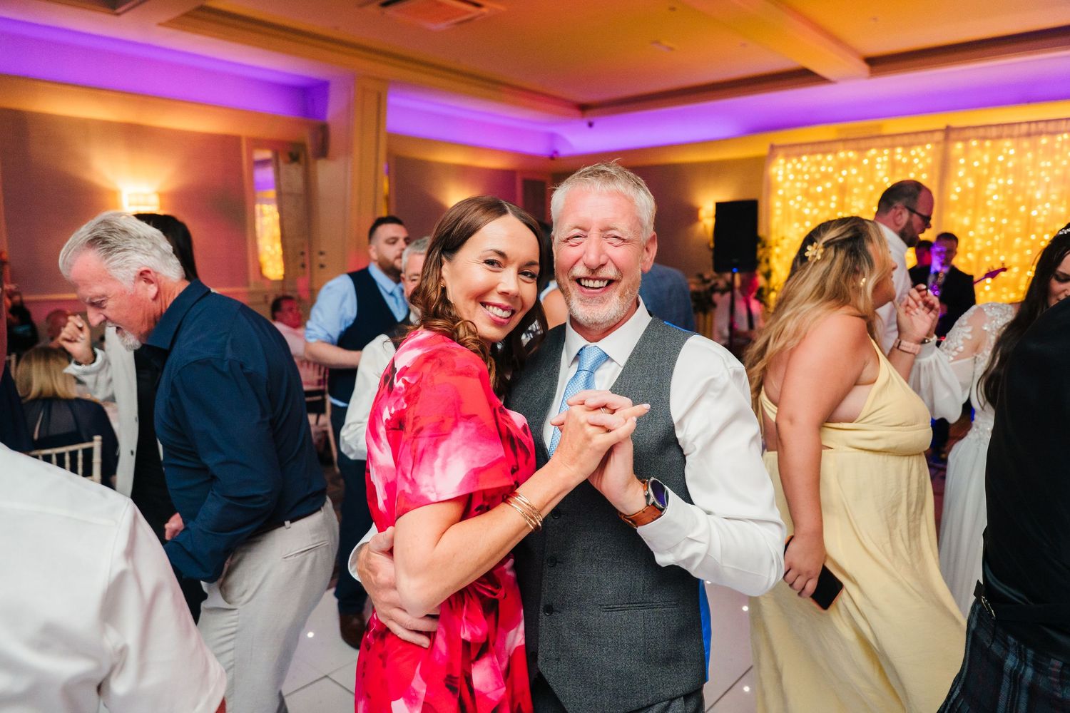 Wedding reception dance party with colorful purple lighting and guests celebrating. Portmarnock Hotel Wedding PHOTOGRAPHER Dublin