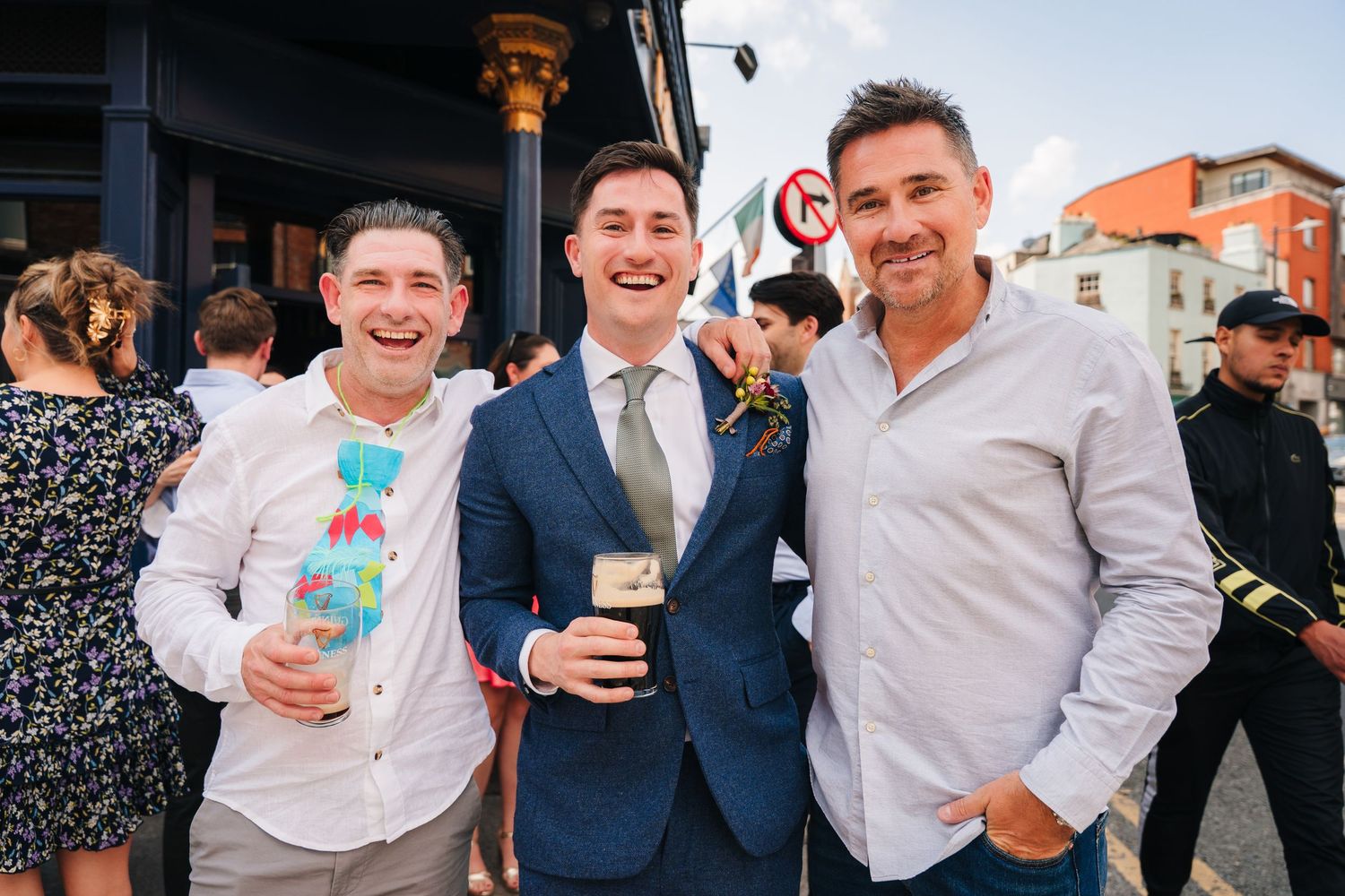 Three friends enjoying drinks together at an outdoor gathering. Same sex wedding PHOTOGRAPHER Dublin