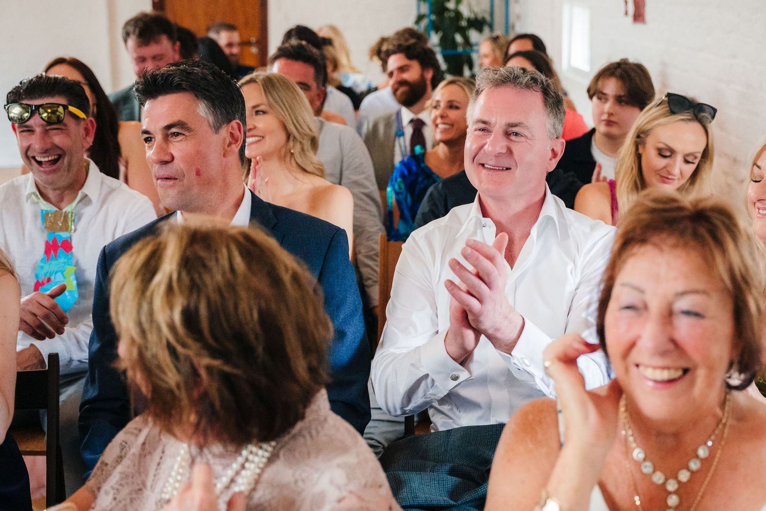 Crowd of wedding guests smiling and clapping during celebration. Same sex wedding PHOTOGRAPHER Dublin