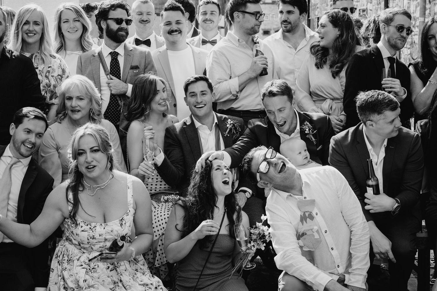 Black and white candid photo of wedding guests laughing and enjoying the celebration together. Same sex wedding PHOTOGRAPHER Dublin