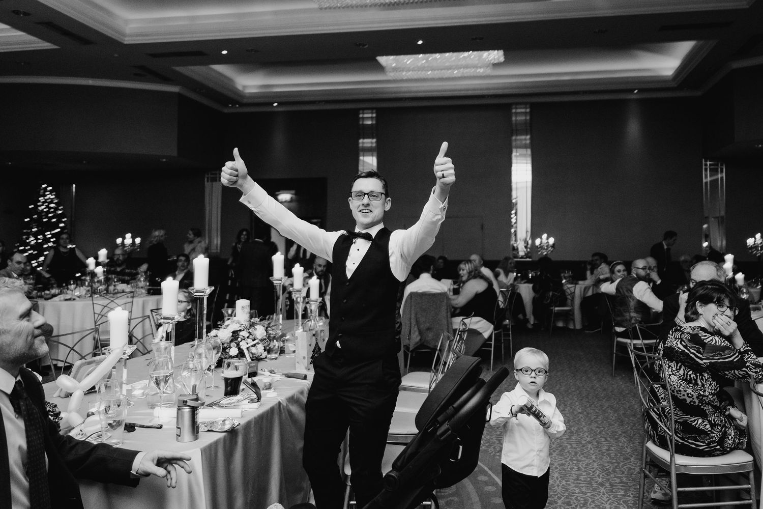 Wedding reception guests celebrate with drinks and dancing in a dimly lit ballroom setting.  Wedding PHOTOGRAPHER Trim Castle