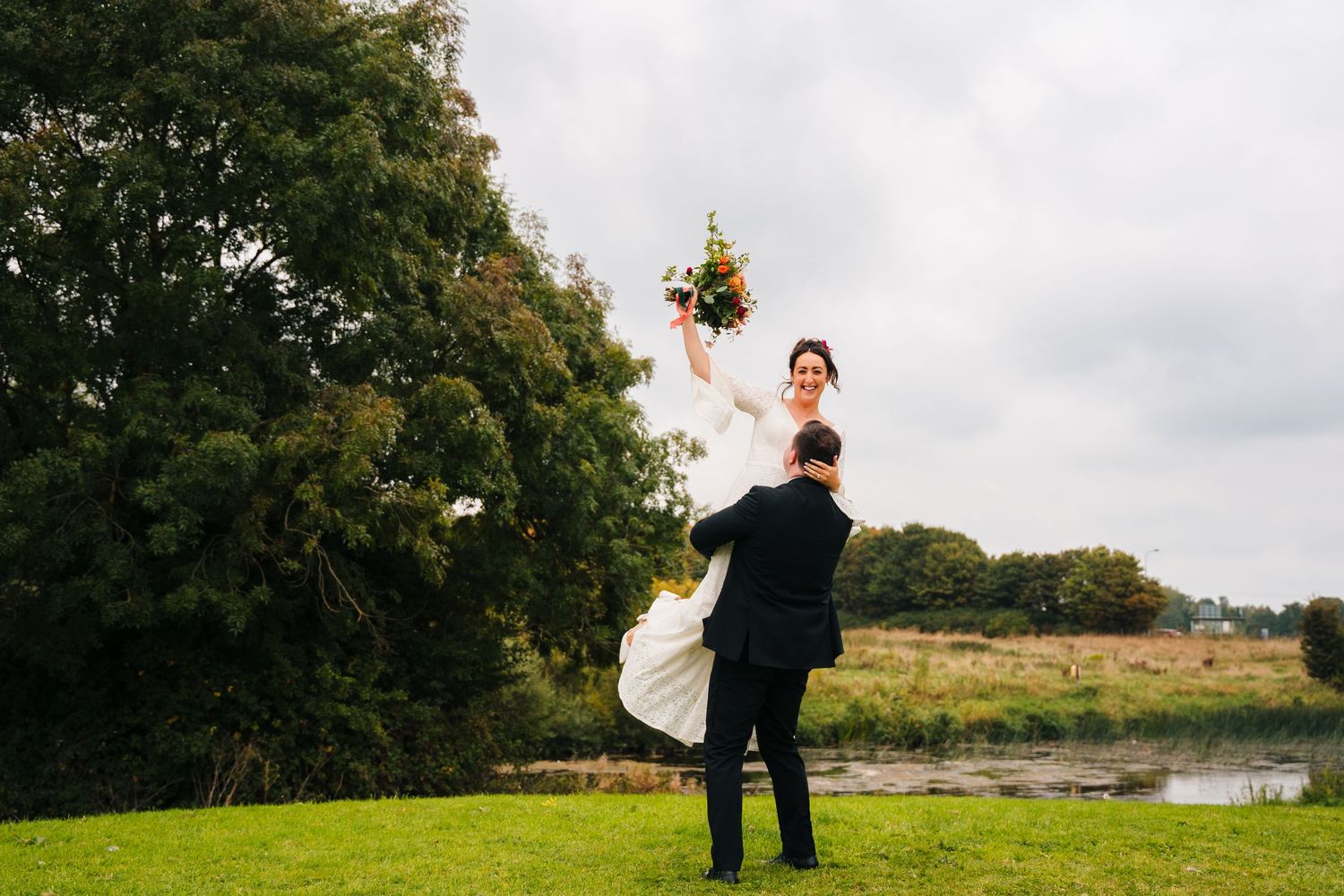 Wedding couple poses in scenic outdoor setting with rolling hills and cloudy sky.Wedding Photography Trim Castle Ireland