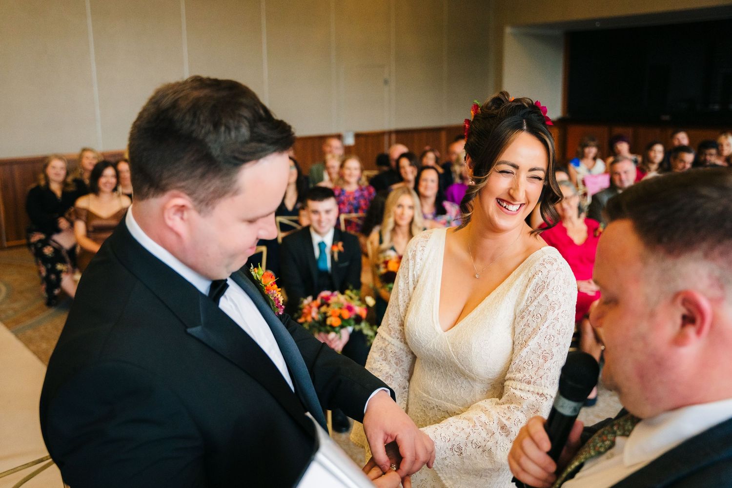 Wedding ceremony in progress with joyful exchange of rings in front of seated guests. Wedding Photography Trim Castle Ireland