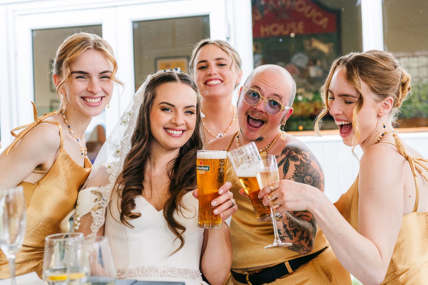 Poulaphouca Wedding photographer wicklow  Group toasting with beer glasses at a festive gathering wearing yellow dresses.