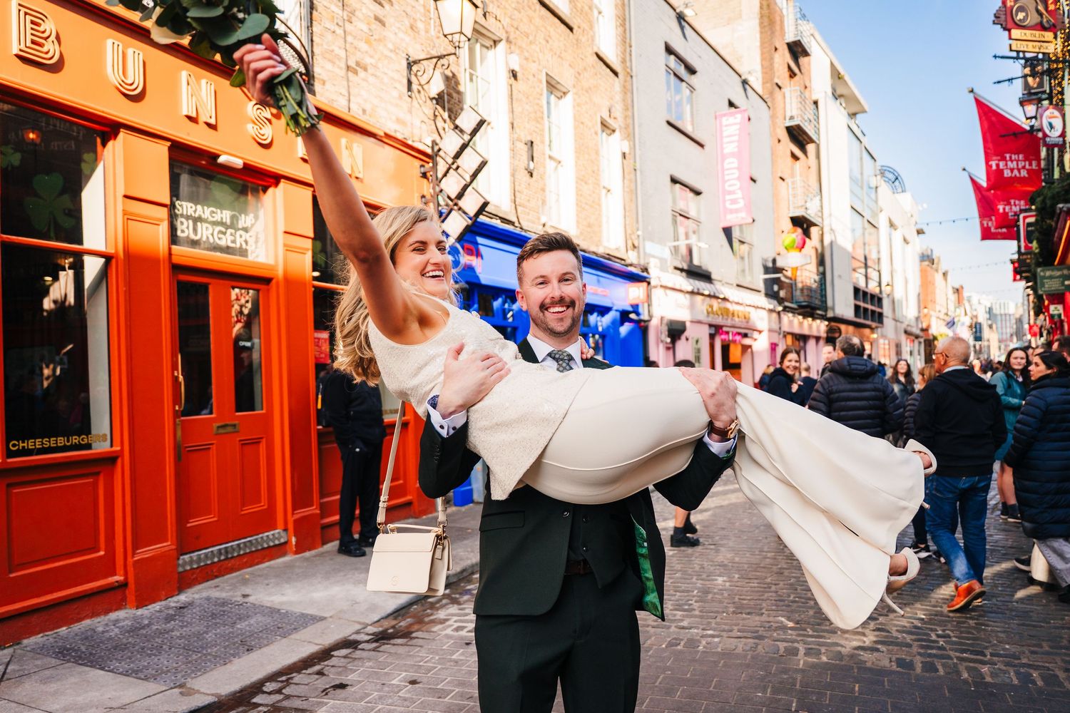 Wedding couple and guests celebrate on a charming European city street with colorfully painted buildings. City Hall Dublin wedding photogrAP