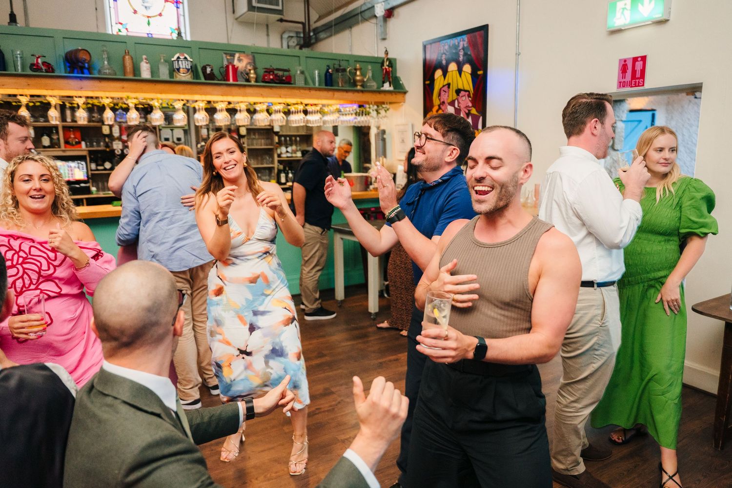 Wedding guests dancing and celebrating at indoor reception venue with wood floors. . Village Barn Tyrrellspass wedding photographer Ireland
