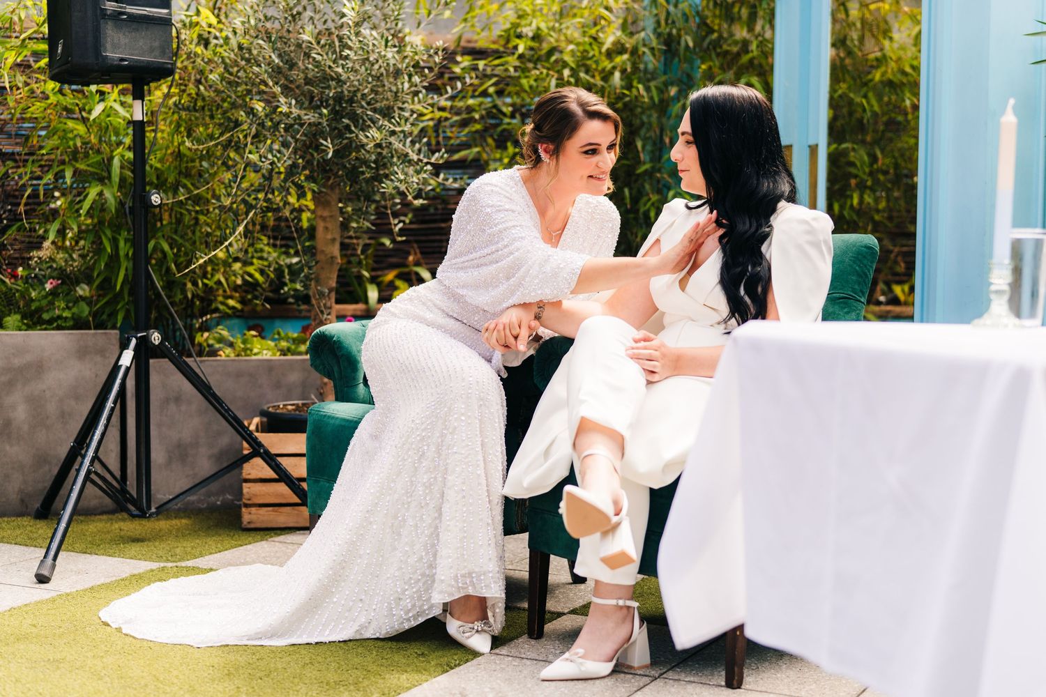 Relaxed outdoor celebration scene with people seated on white chairs in a garden setting. House Dublin Wedding Photographer