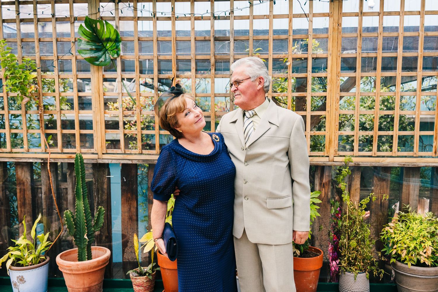 People enjoying conversation and laughter in front of a wooden lattice garden backdrop with potted plants. House Dublin Wedding Photographer