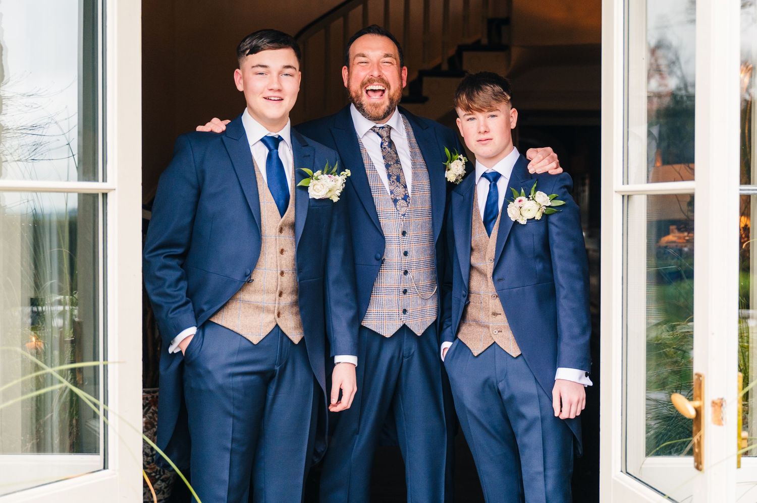 A group of groomsmen in coordinated navy suits and gray vests pose together at a wedding venue. Virginia Park Lodge Wedding Photographer Dub