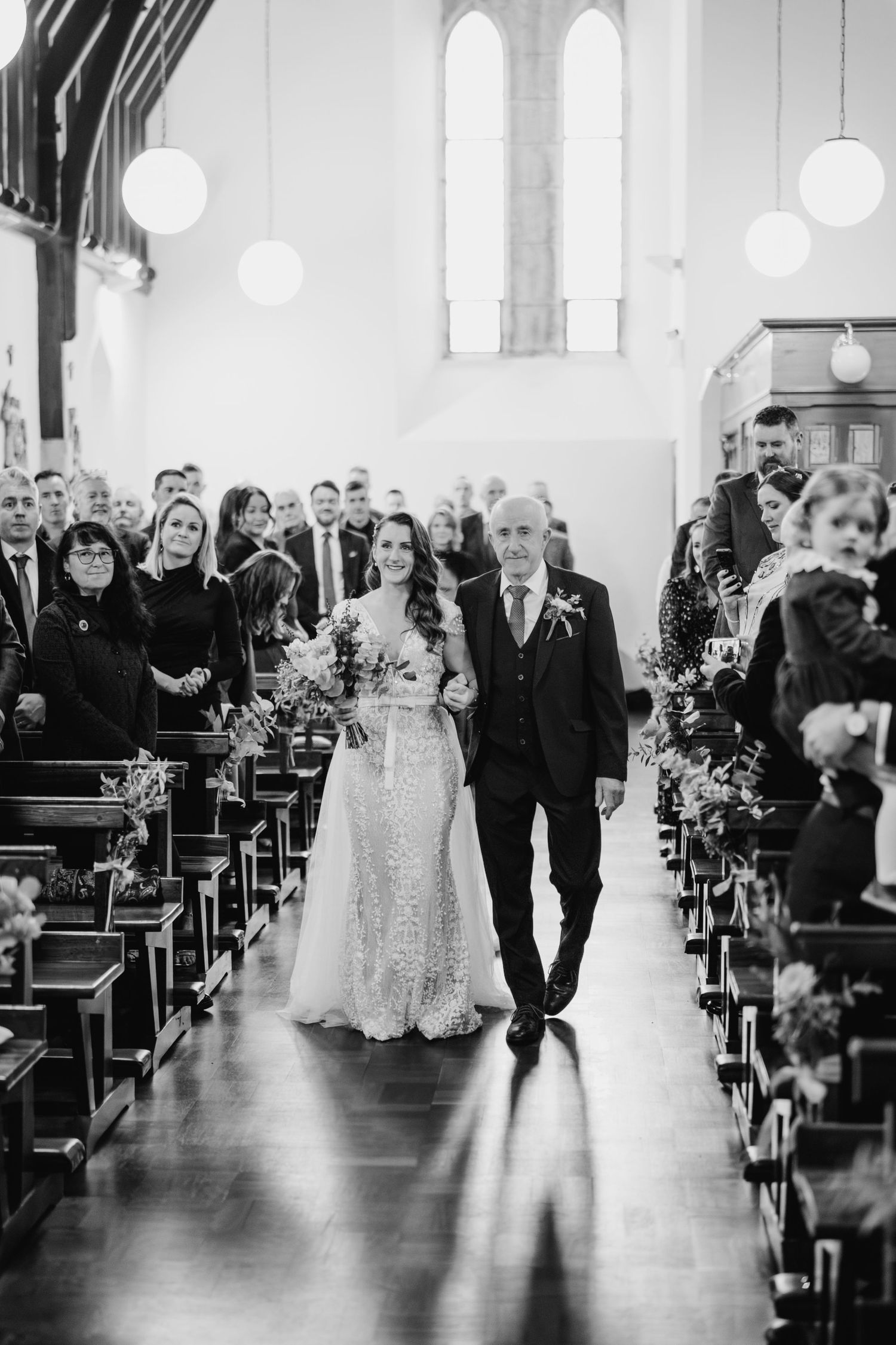 Black and white photo showing wedding guests seated in church pews during an elegant ceremony.