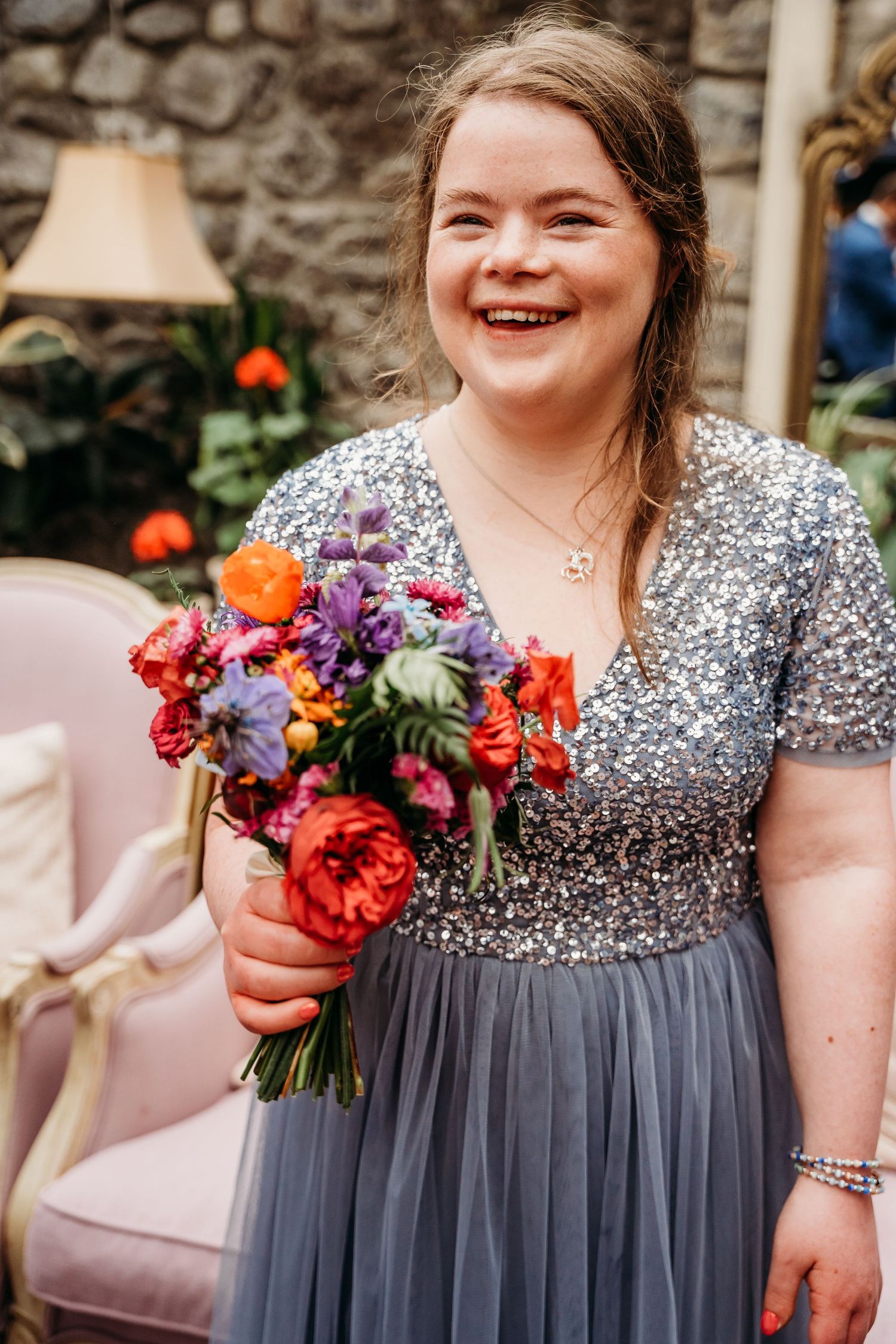 Person in sparkly grey dress holding colorful bouquet of flowers while smiling brightly. Wedding photographer Dublin