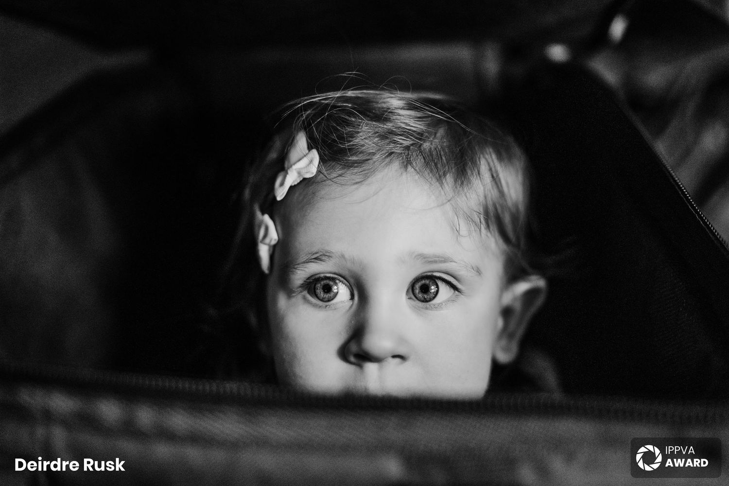 A close-up black and white portrait shows a child's innocent expression through a window. PHOTOGRAPHER Dublin