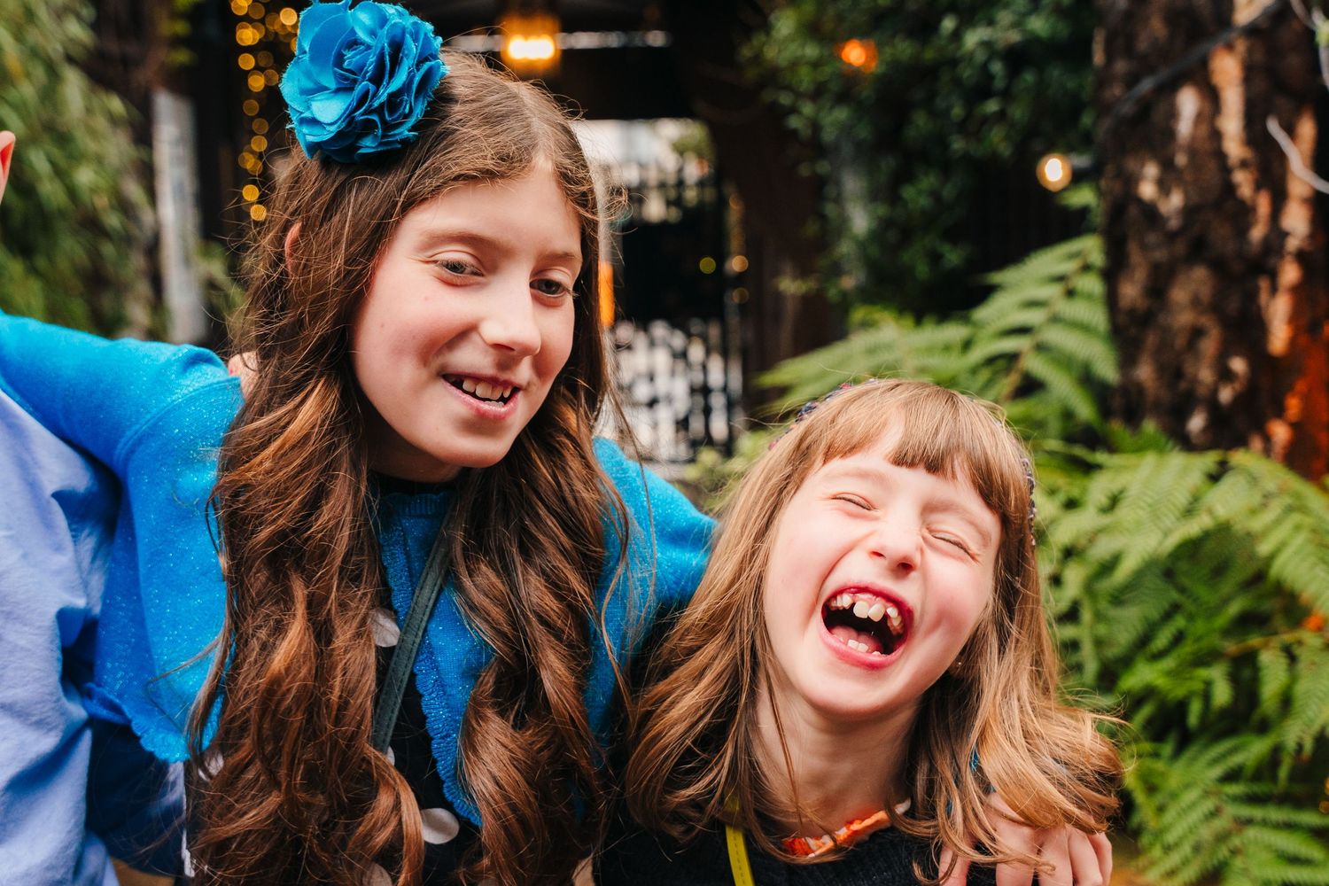 Two guests sharing joyful laughter in garden setting with ferns. Marco Pierre Dublin Wedding Photographer