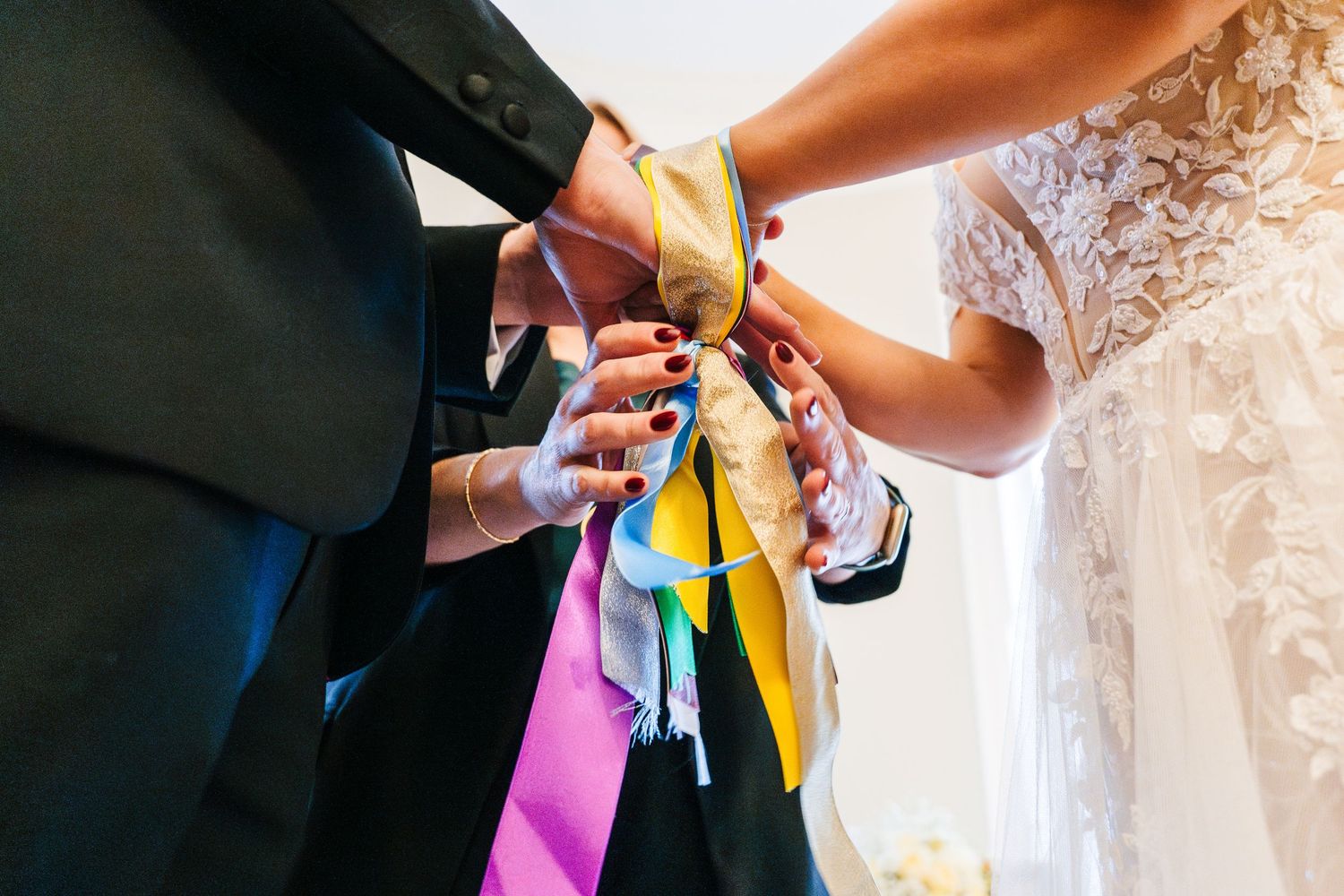 Close-up of hands tying colorful ribbons during a wedding ceremony.  Wedding PHOTOGRAPHER Dublin