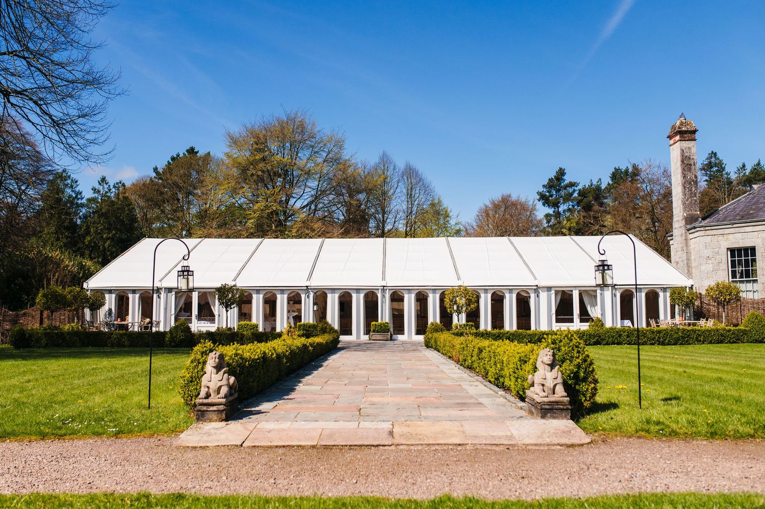 Castle Leslie Wedding Photographer Dublin Panoramic view of a grand white columned ceremony venue with a long pathway on a sunny day.
