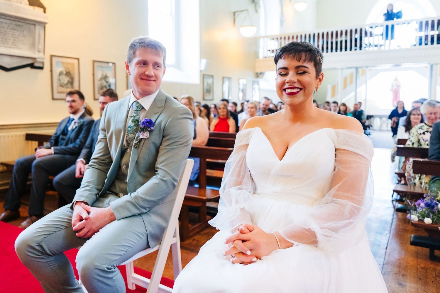 A couple celebrates joyfully during their wedding ceremony in a bright indoor venue filled with guests.Millhouse slane wedding photographer