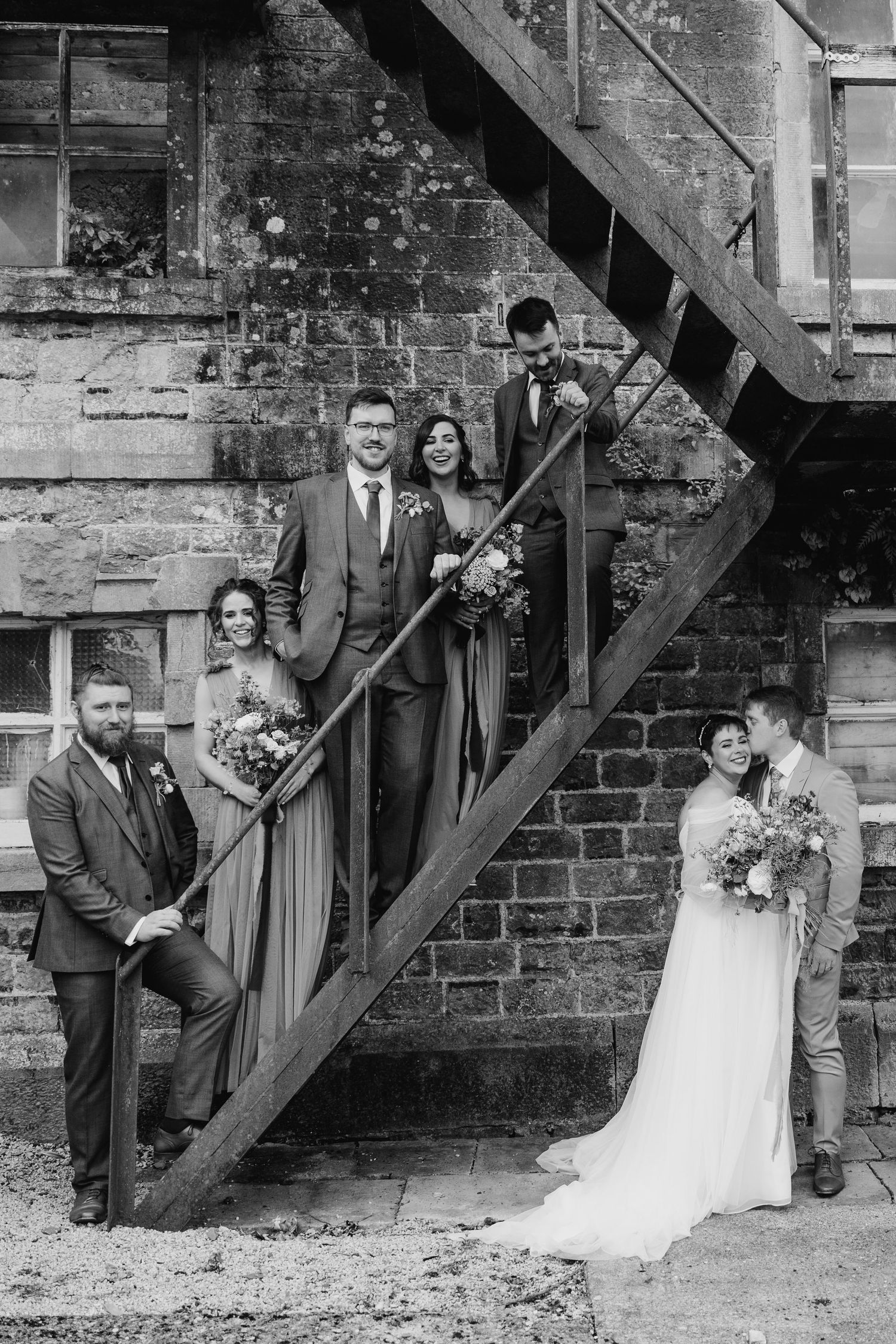 Millhouse slane wedding photograpWedding couple poses against rustic brick wall and wooden beams in five artistic black and white portraits.