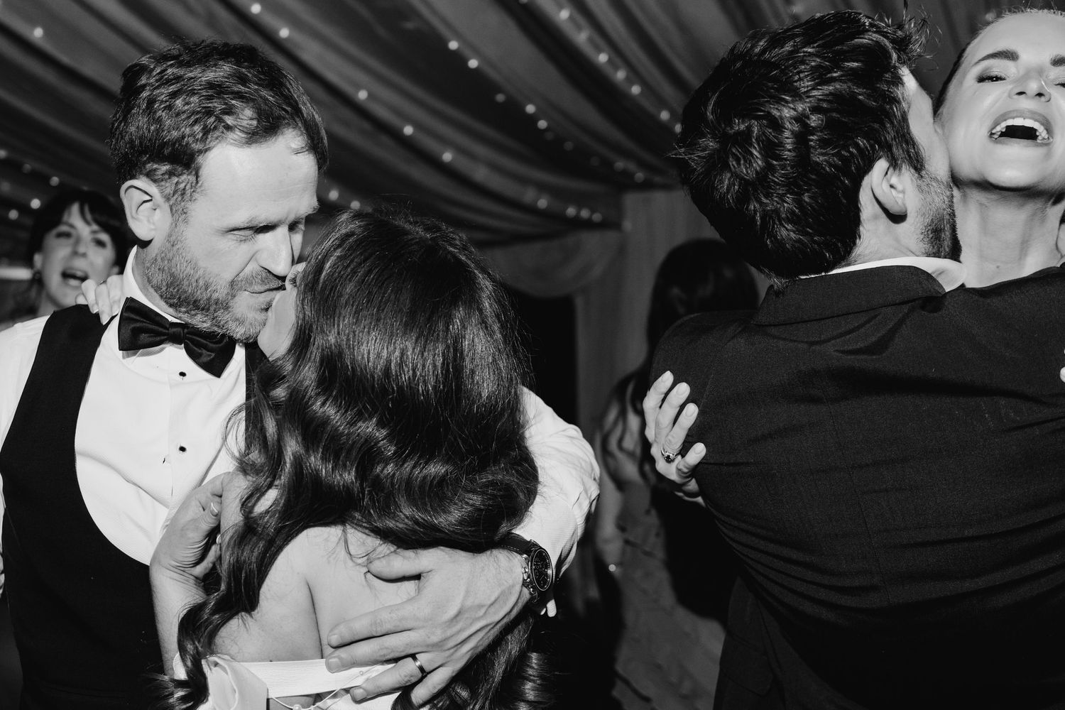 Castle Leslie Wedding Photographer DublBlack and white photo of wedding guests dancing and embracing during a lively reception celebration.