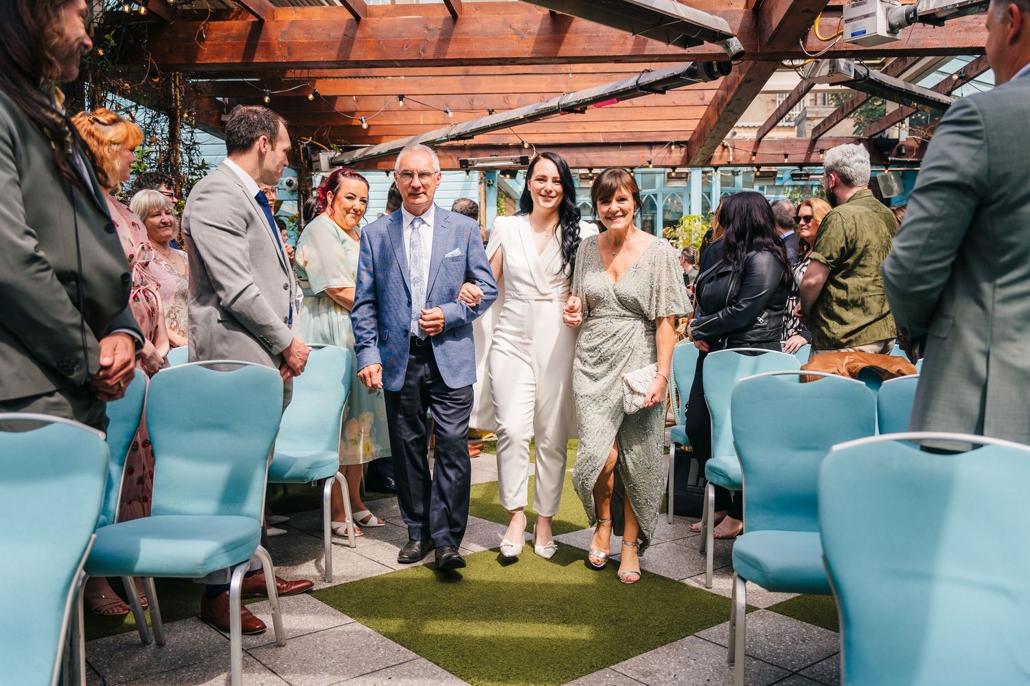 Guests mingle under a covered outdoor venue with blue seating and terracotta roof. House Dublin Wedding Photographer