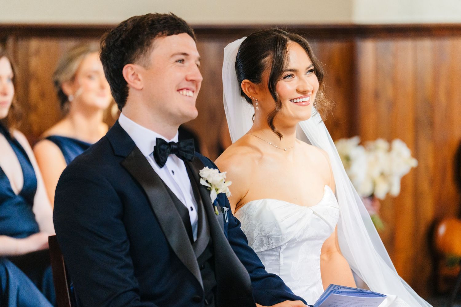 Wedding guests laugh together during a reception in an elegant wood-paneled venue. Virginia Park Lodge Wedding photographer Dublin Ireland