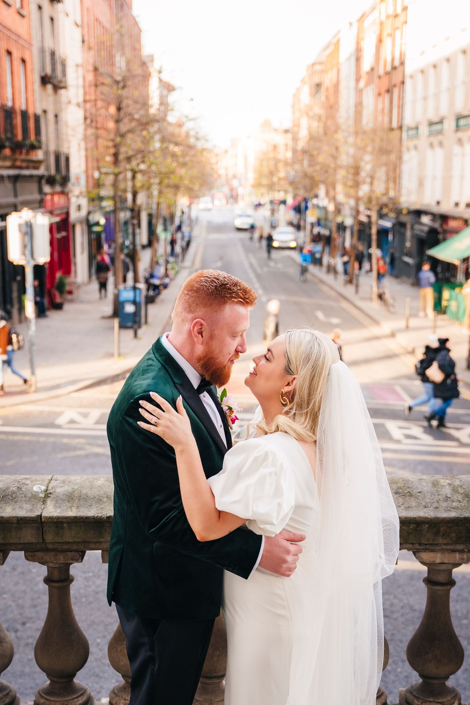 A romantic wedding photo sequence showing a couple sharing kisses against a scenic urban backdrop with stone balustrades. Wedding photograph