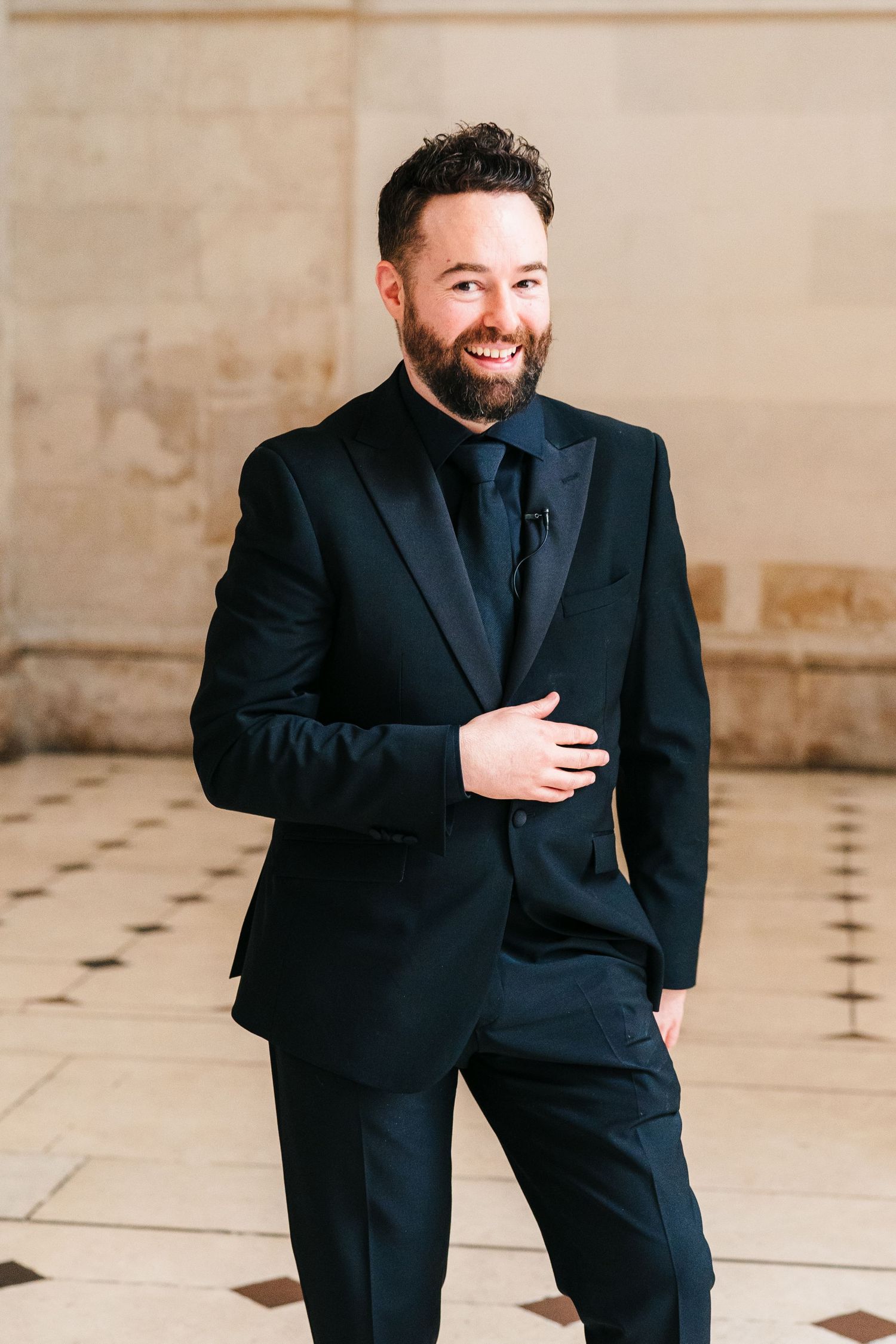 A series of candid moments showing a person in a black suit laughing and gesturing expressively against a light background.  city hall dubli