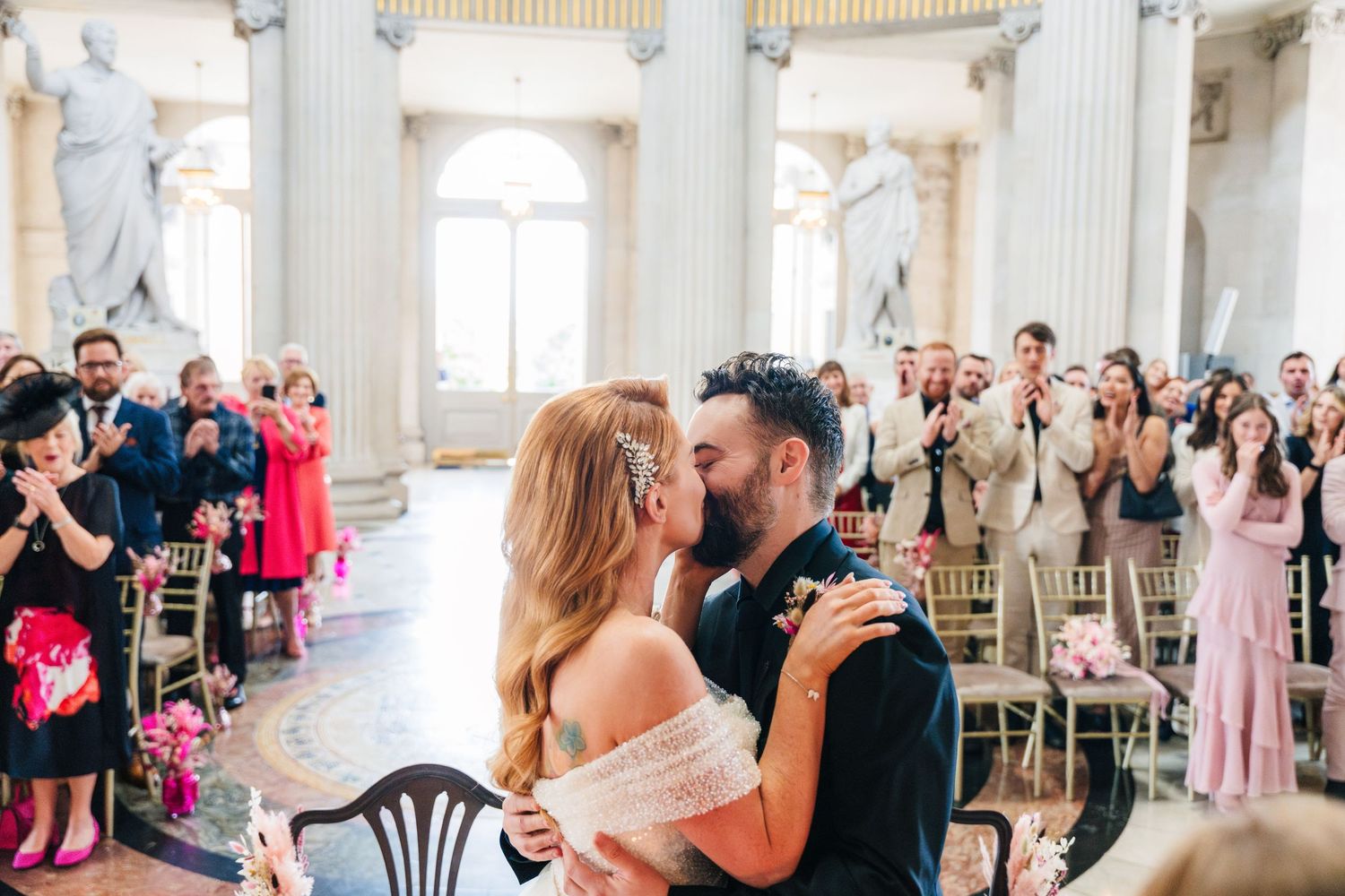 Wedding celebration in a grand ballroom with white columns and guests seated at round tables.  city hall dublin wedding photos
