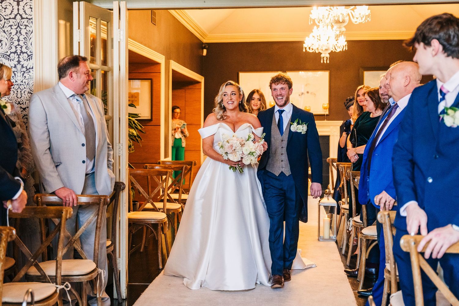 Wedding reception venue decorated with elegant chandeliers and white seating.  Virginia Park Lodge Wedding Photographer Cavan Dublin Ireland