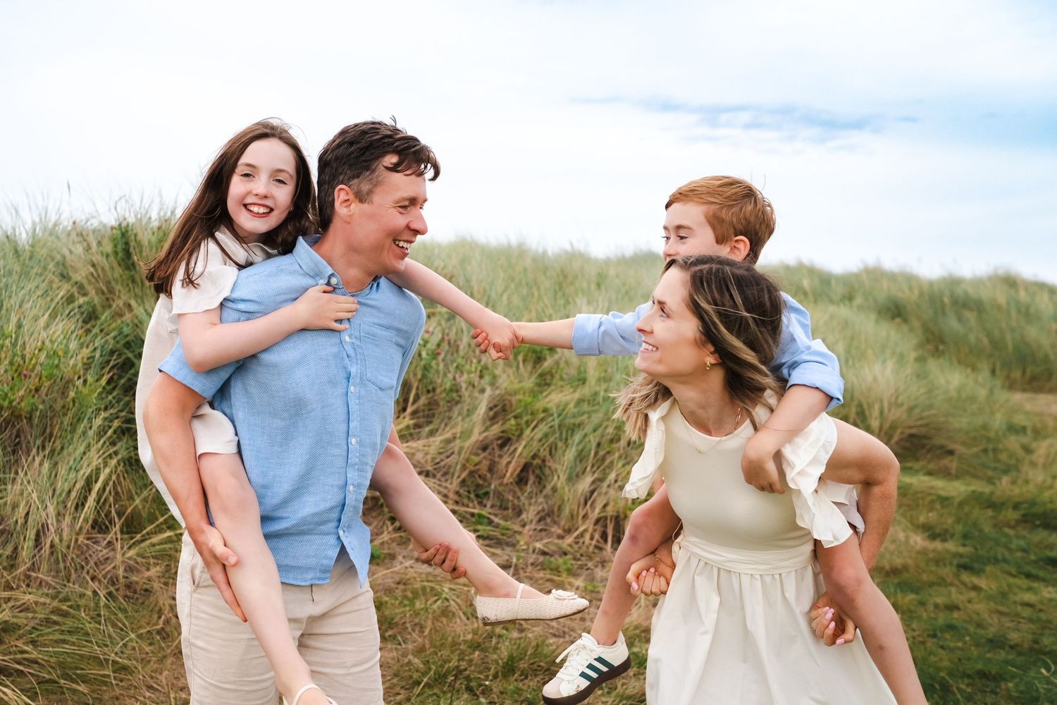 Candid moments of a couple playing and laughing together on a scenic coastal hillside.  Family photographer Dublin Ireland