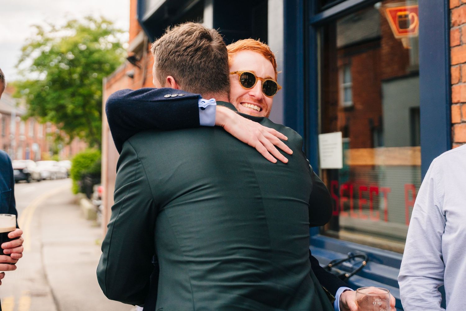 Two people share a warm embrace on a city street during a celebration.Same sex wedding PHOTOGRAPHER Dublin
