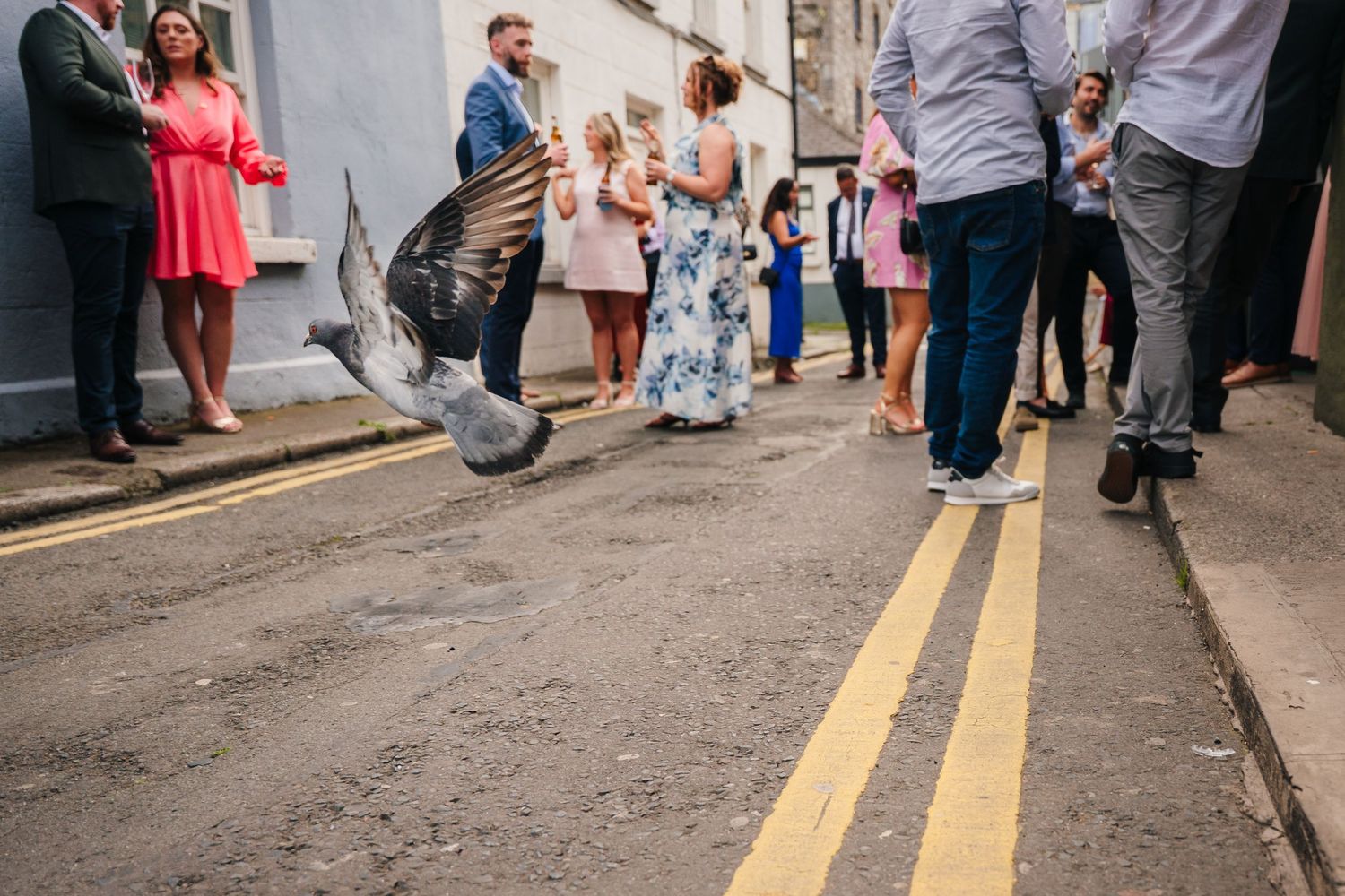 Wedding guests walking down a street with yellow lines. Same sex wedding PHOTOGRAPHER Dublin
