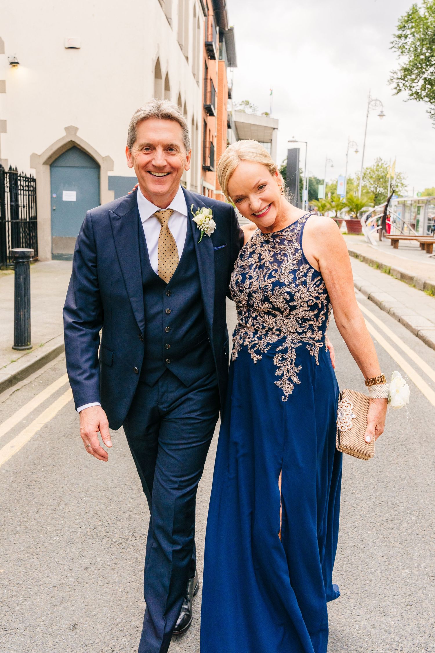 A couple dressed in formal attire poses on an urban street with architectural details in the background. PHOTOGRAPHER Dublin Ireland Wedding