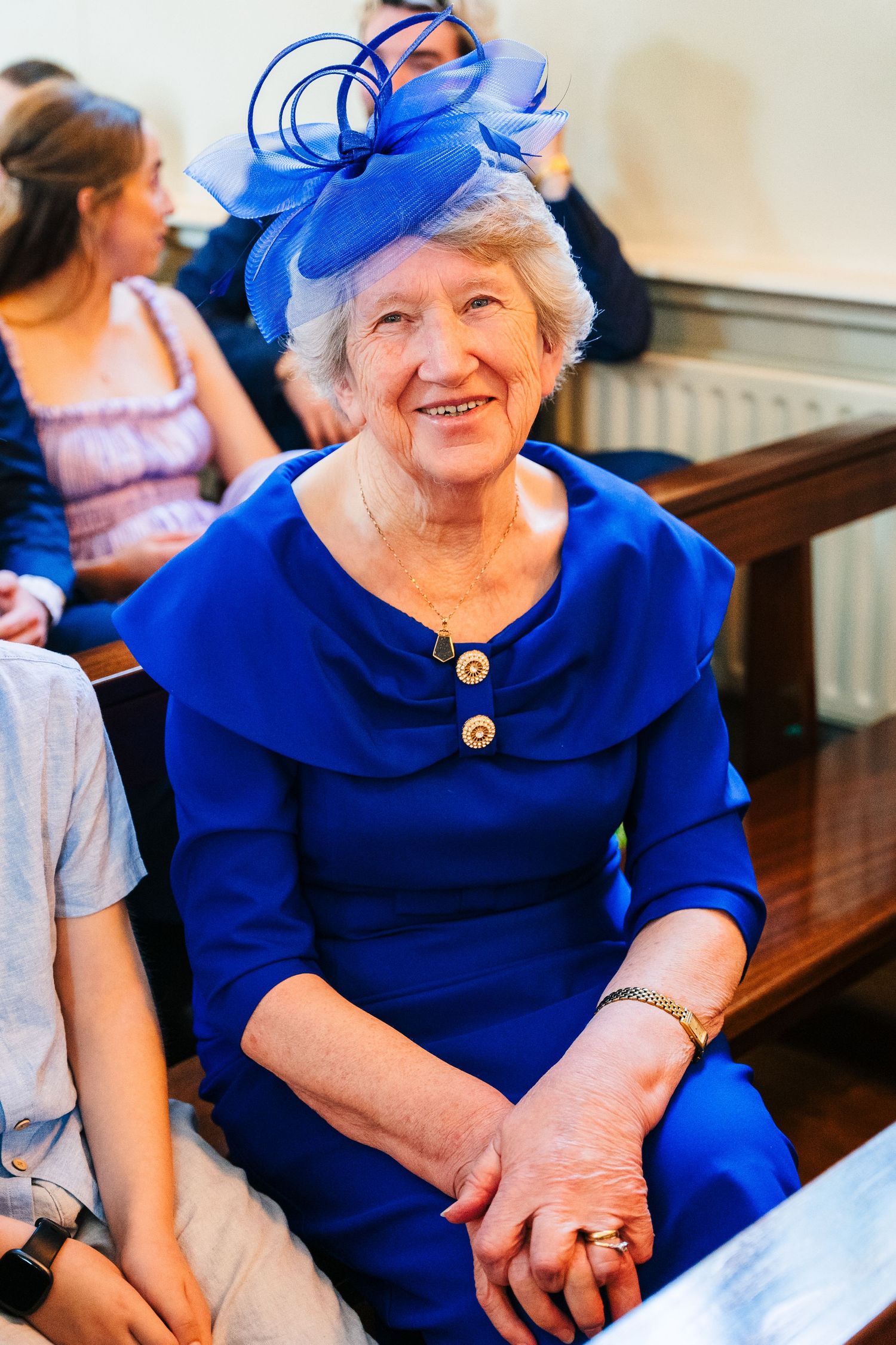 Millhouse slane wedding photographer dublin Woman in bright blue dress and matching fascinator sitting in church pew.