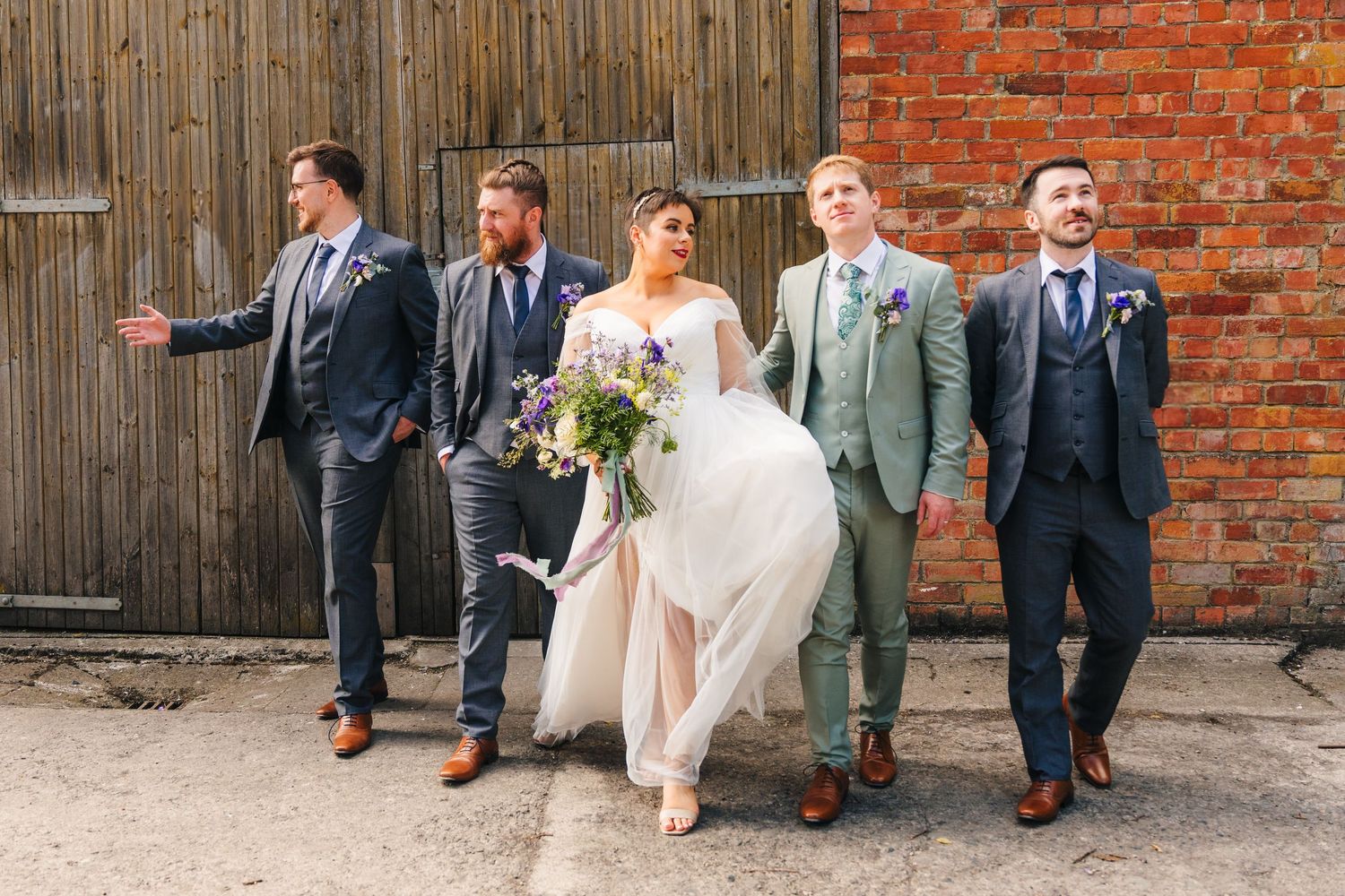 Millhouse slane wedding photographer dublin Wedding party posing against rustic brick wall backdrop in formal attire.