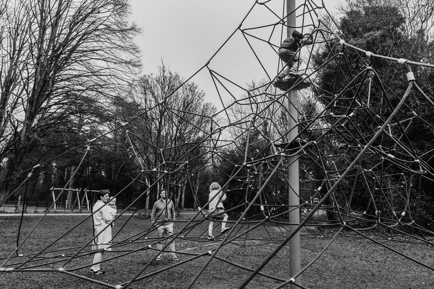 Family photographer Dublin Ireland Black and white image of children climbing on playground equipment.