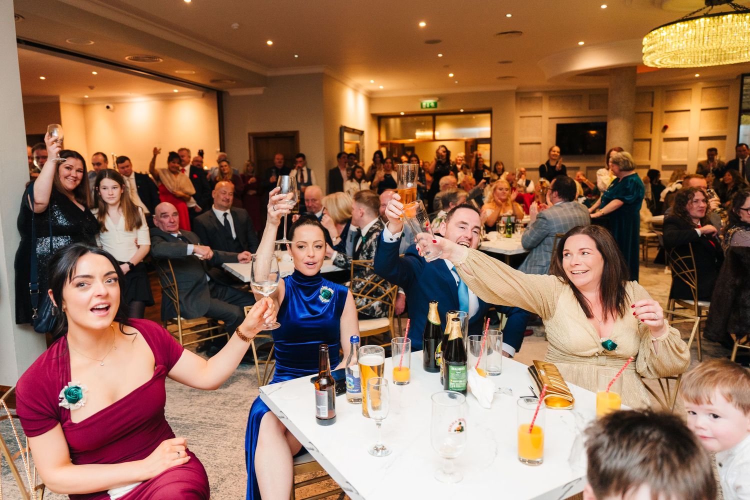 Wedding reception guests raising their drinks in celebration at tables.  Wedding PHOTOGRAPHER Trim Castle